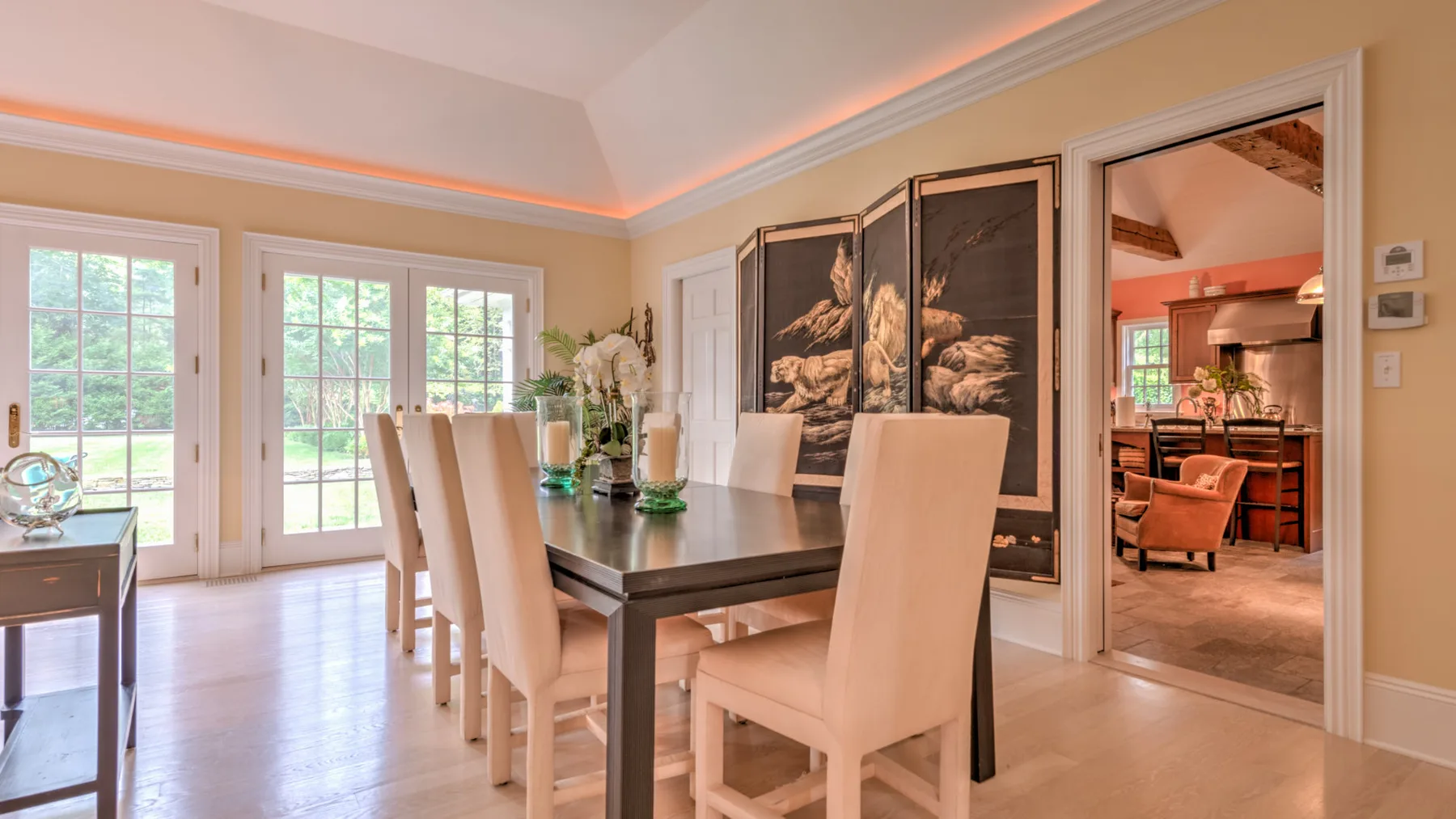 Un comedor luminoso con una mesa oscura y ventanales que dan a zonas verdes.
