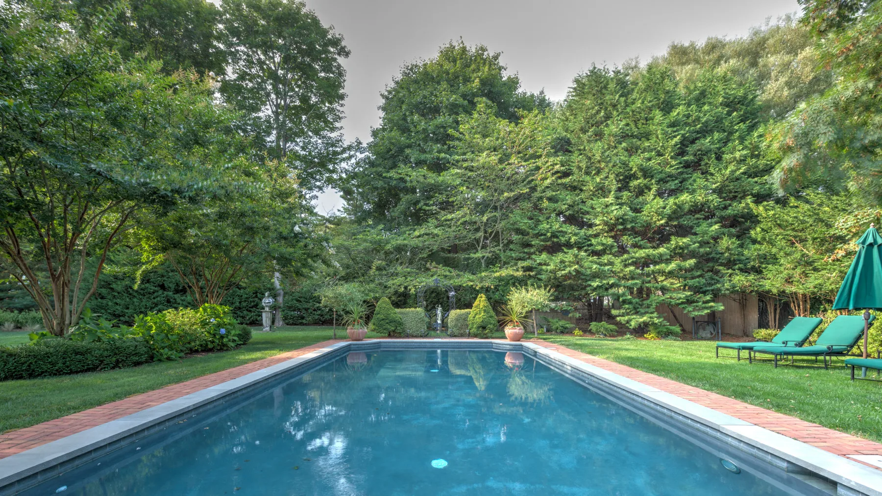 Una piscina rodeada de árboles y césped verde.