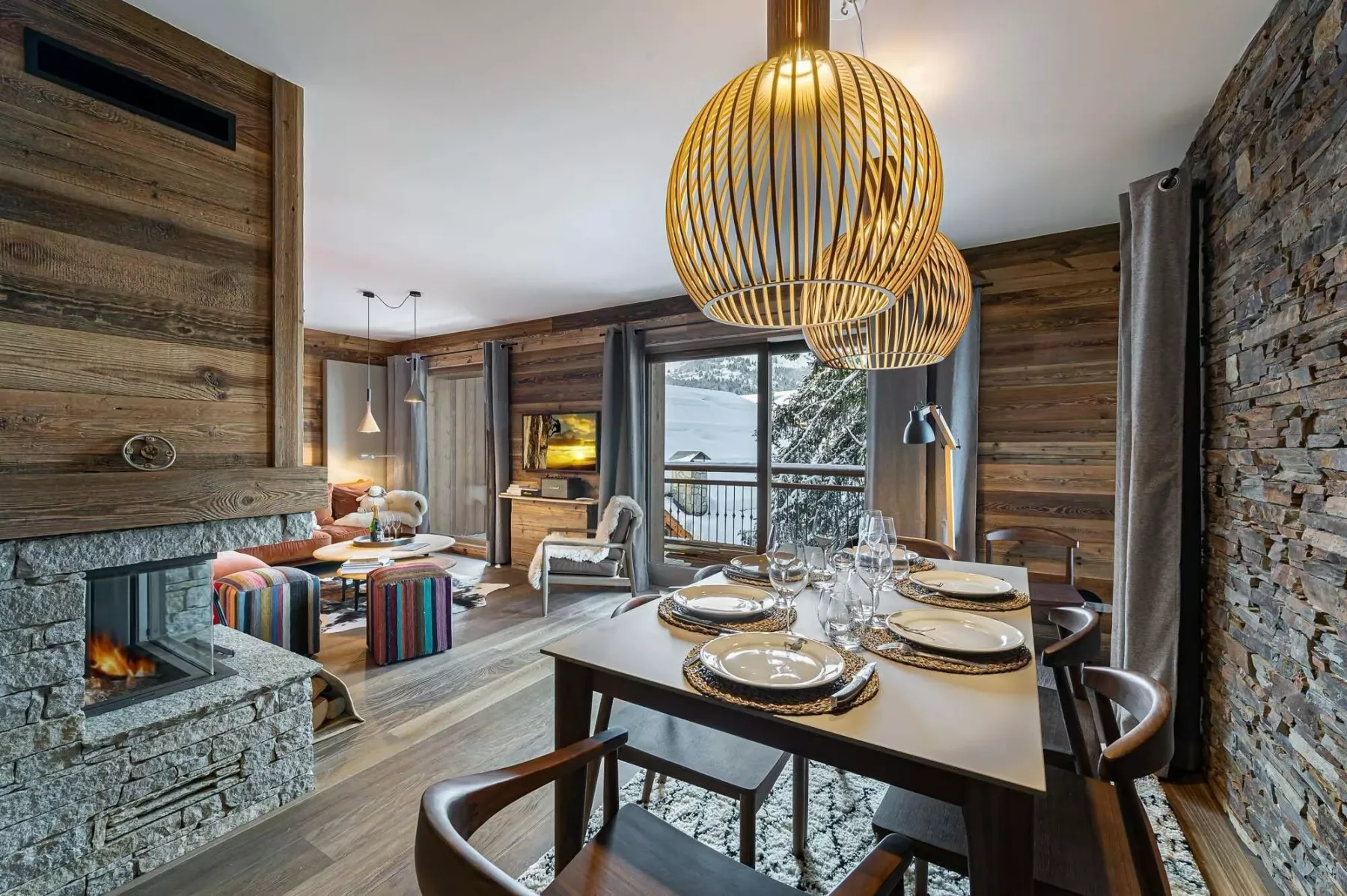 Comedor revestido de madera con una mesa puesta y una chimenea de piedra.
