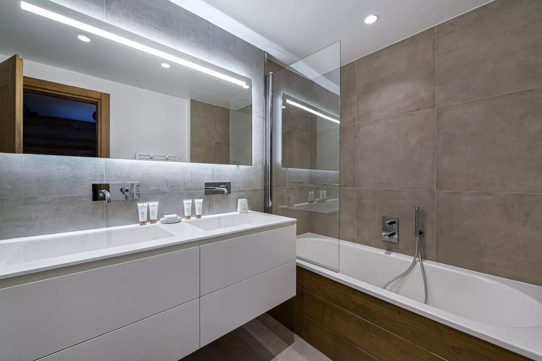 Un baño moderno con un lavabo amplio y una bañera junto a un panel de vidrio.