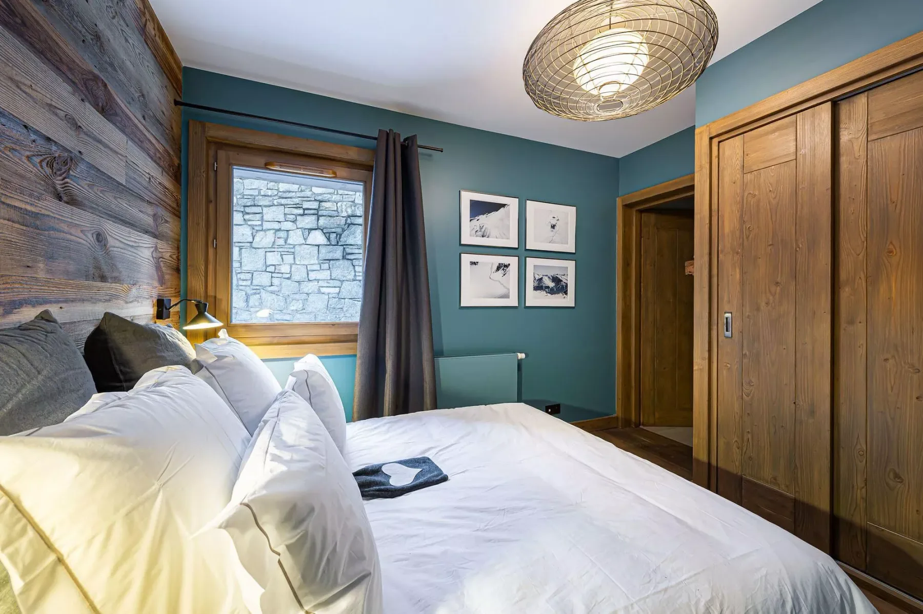 Un dormitorio con una cama, paredes verde azulado y una ventana.