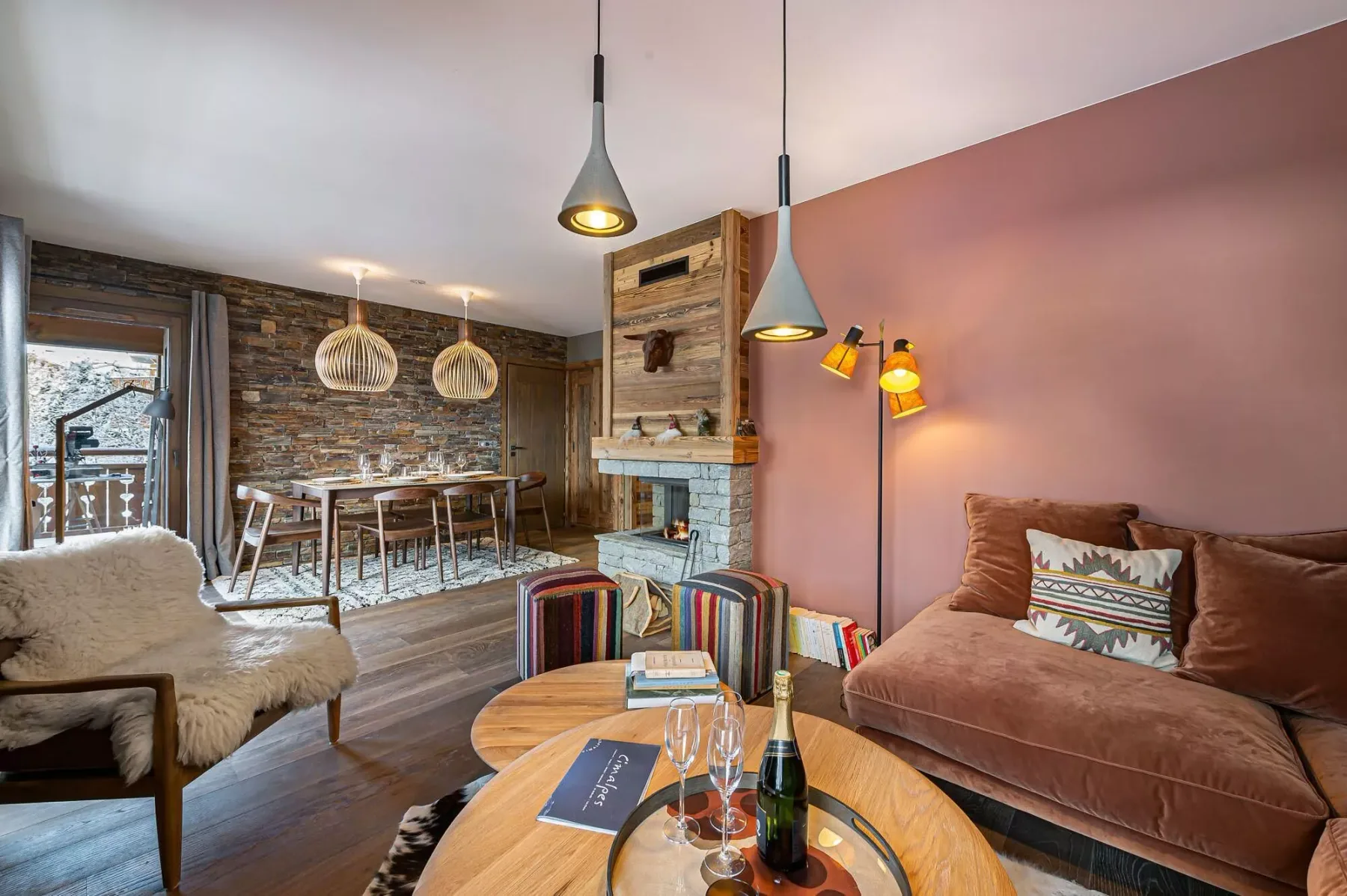 Una sala de estar con chimenea, asientos bajos y un comedor junto a la ventana.