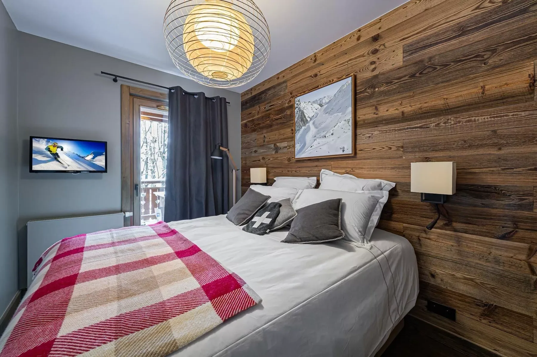 Un dormitorio con una cama vestida de blanco y una manta de cuadros coloridos.