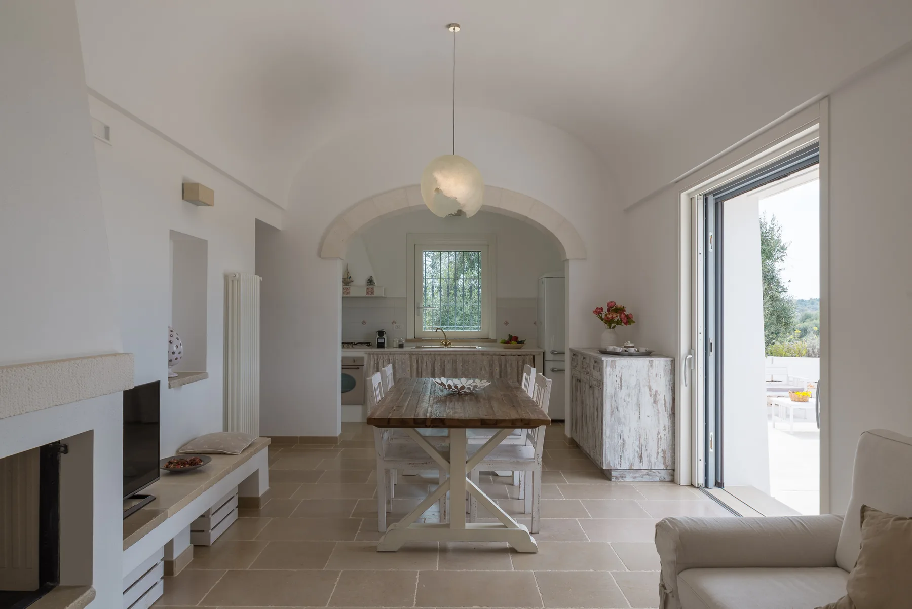 A bright kitchen and dining area with an arched opening and a table.