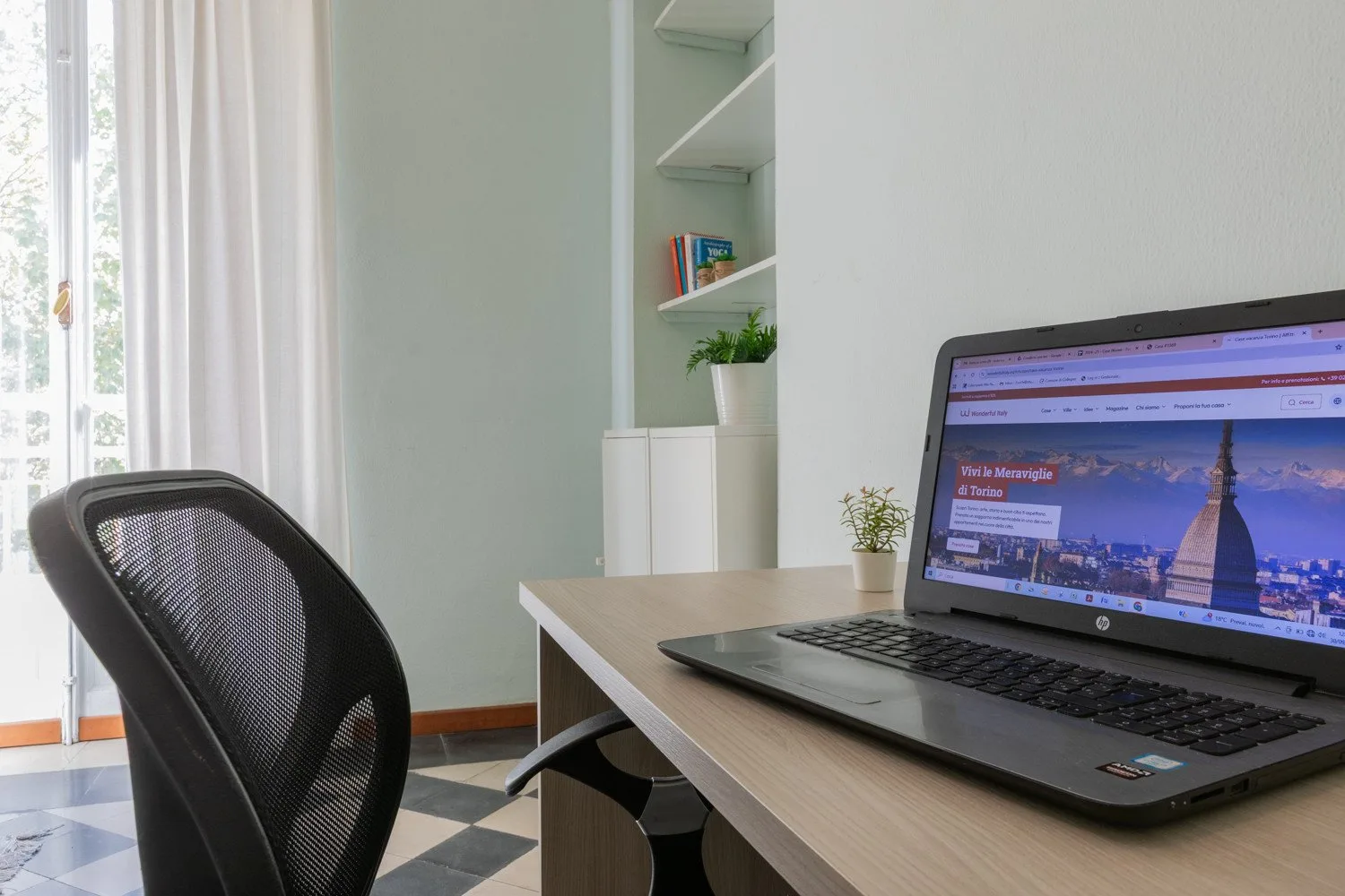 Un espacio de trabajo luminoso con una computadora portátil sobre un escritorio junto a una silla de respaldo de malla.