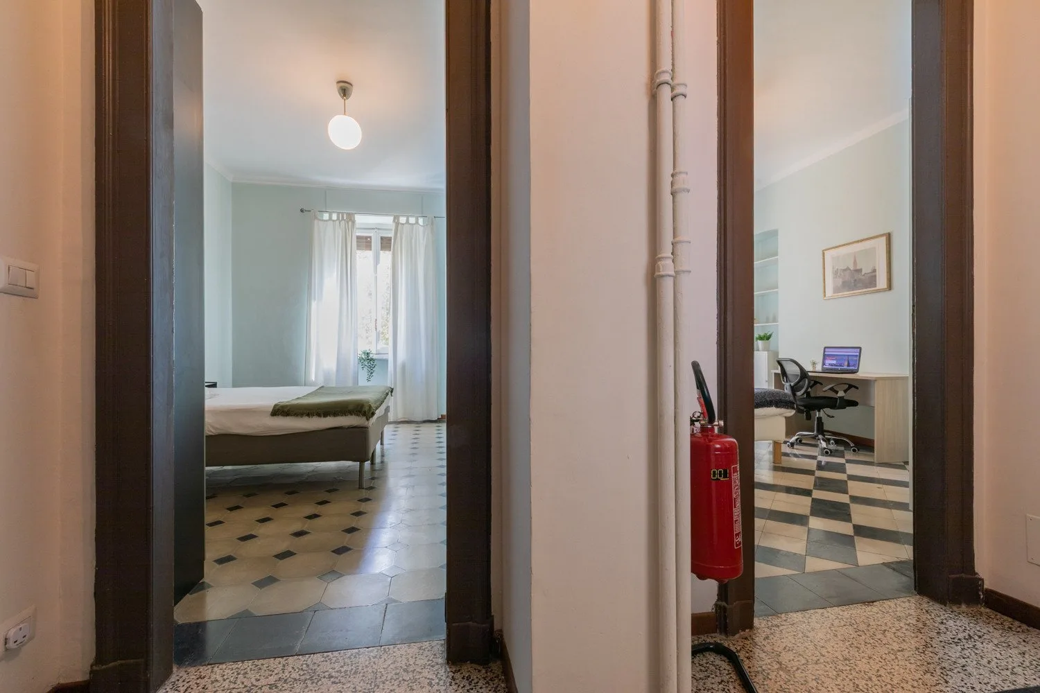 Una puerta del pasillo da a un dormitorio y una pequeña oficina.