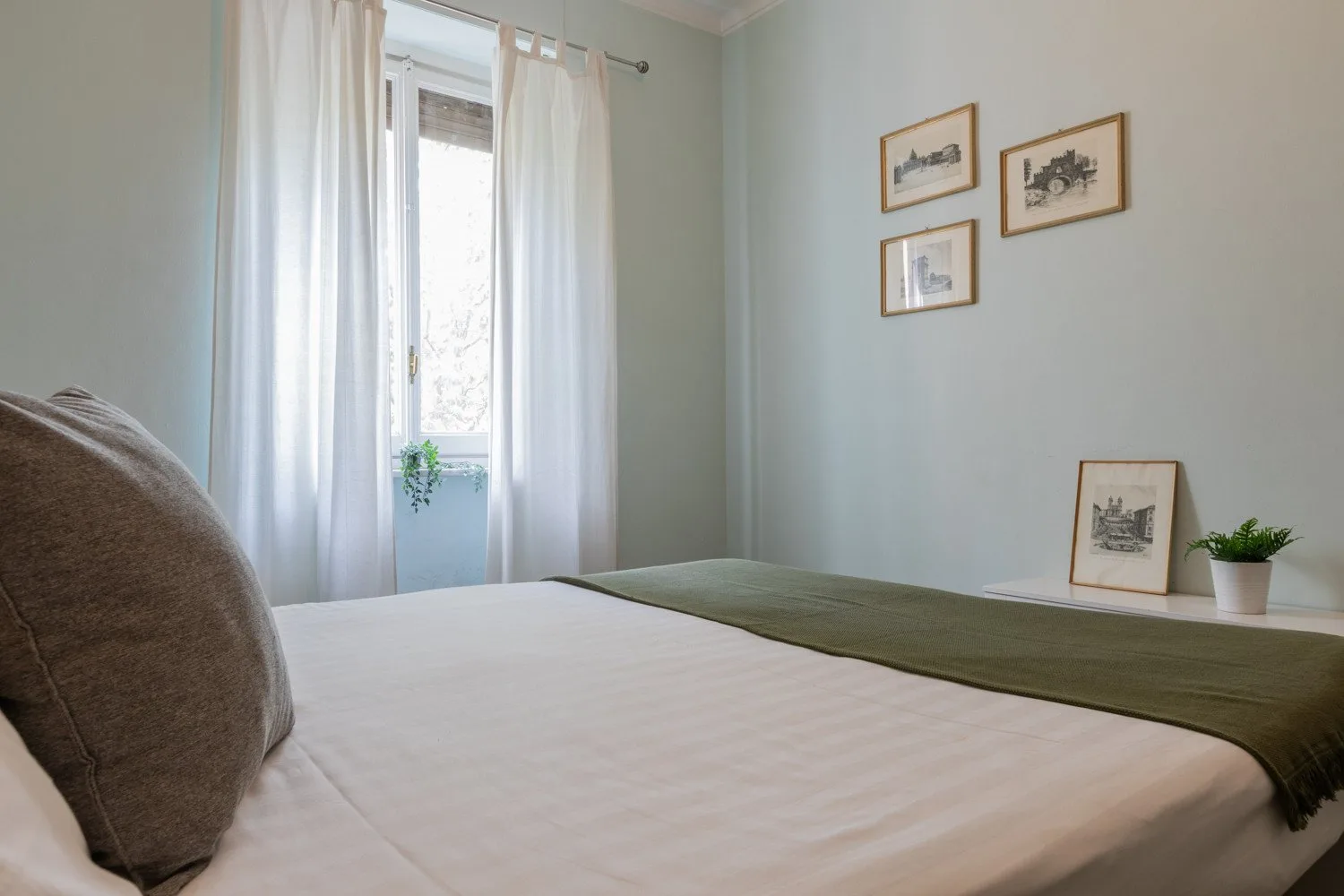 Un dormitorio con una cama bien tendida y cuadros enmarcados en la pared.