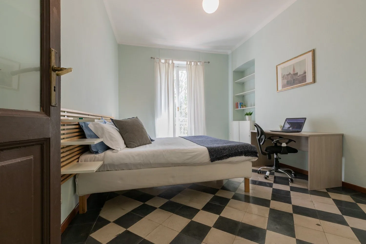 Un dormitorio con una cama, un escritorio y un suelo de baldosas estampadas.
