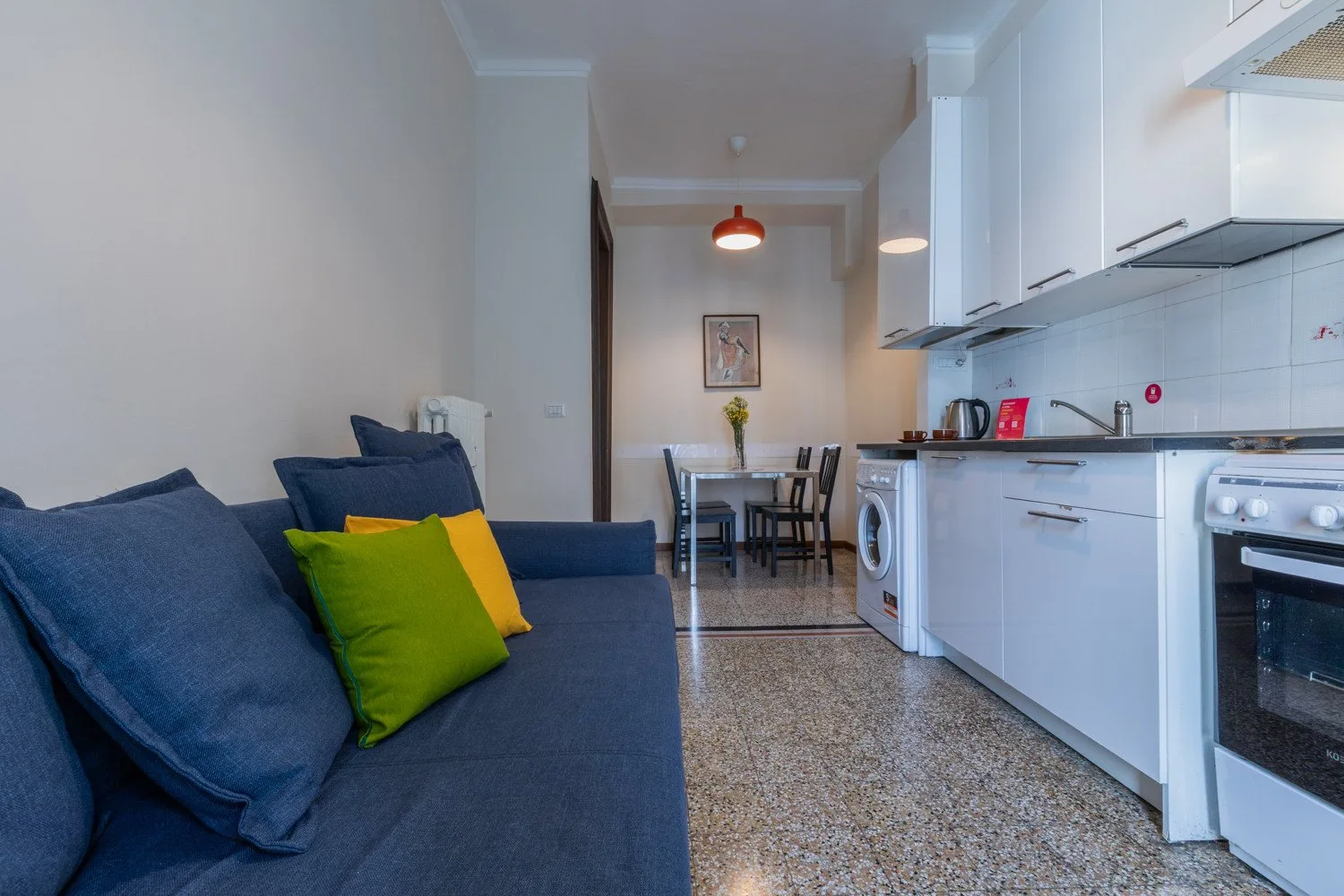 Una sala de estar y cocina integradas, con una mesa de comedor al fondo.