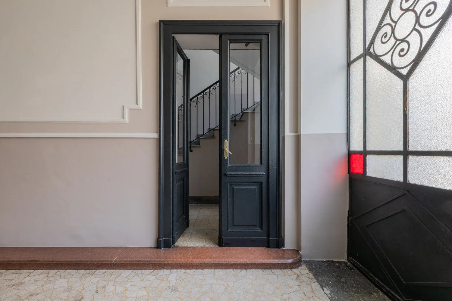 Una entrada con una puerta oscura da a una escalera.