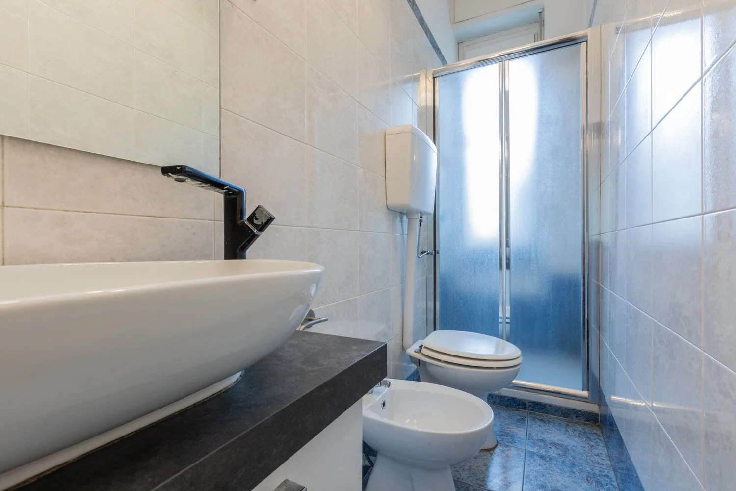 Un baño con azulejos, lavabo, inodoro y ducha.