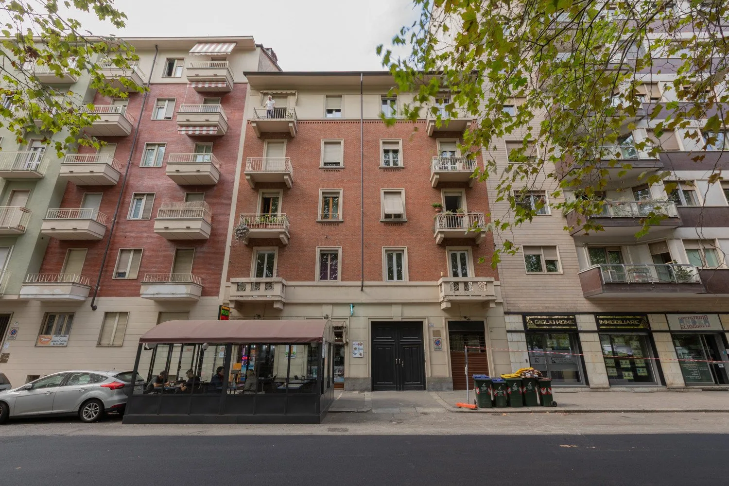 Un edificio de apartamentos de varios pisos con balcones y locales comerciales en la planta baja.