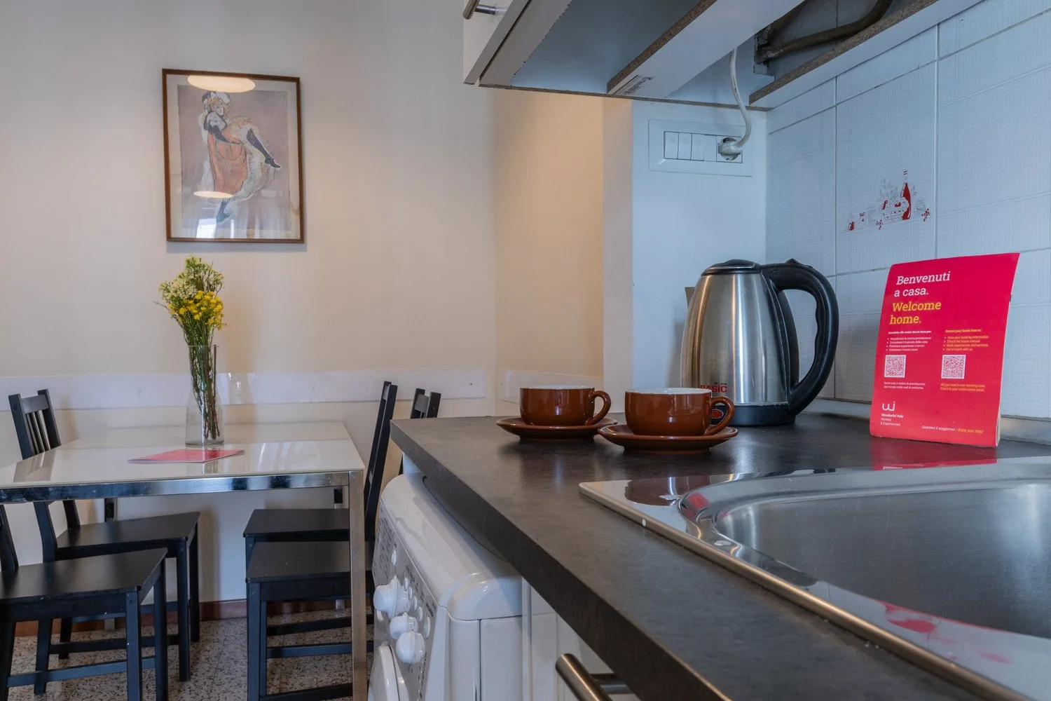 Una pequeña cocina con hervidor y mesa de comedor.