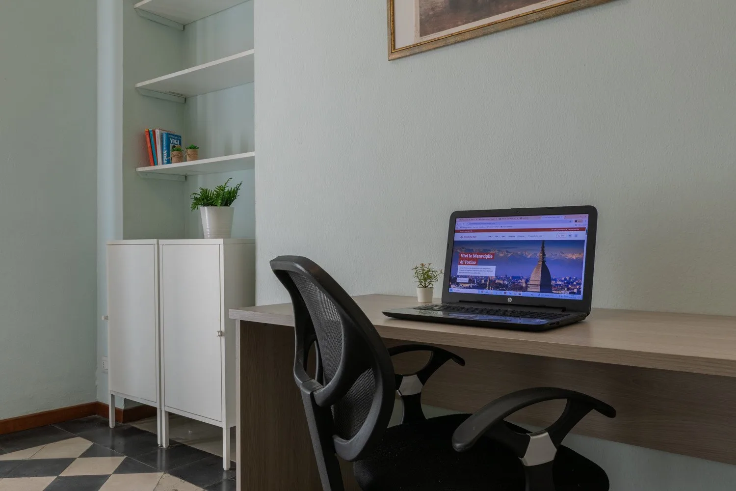 Un escritorio con una computadora portátil y una silla está junto a estantes empotrados.