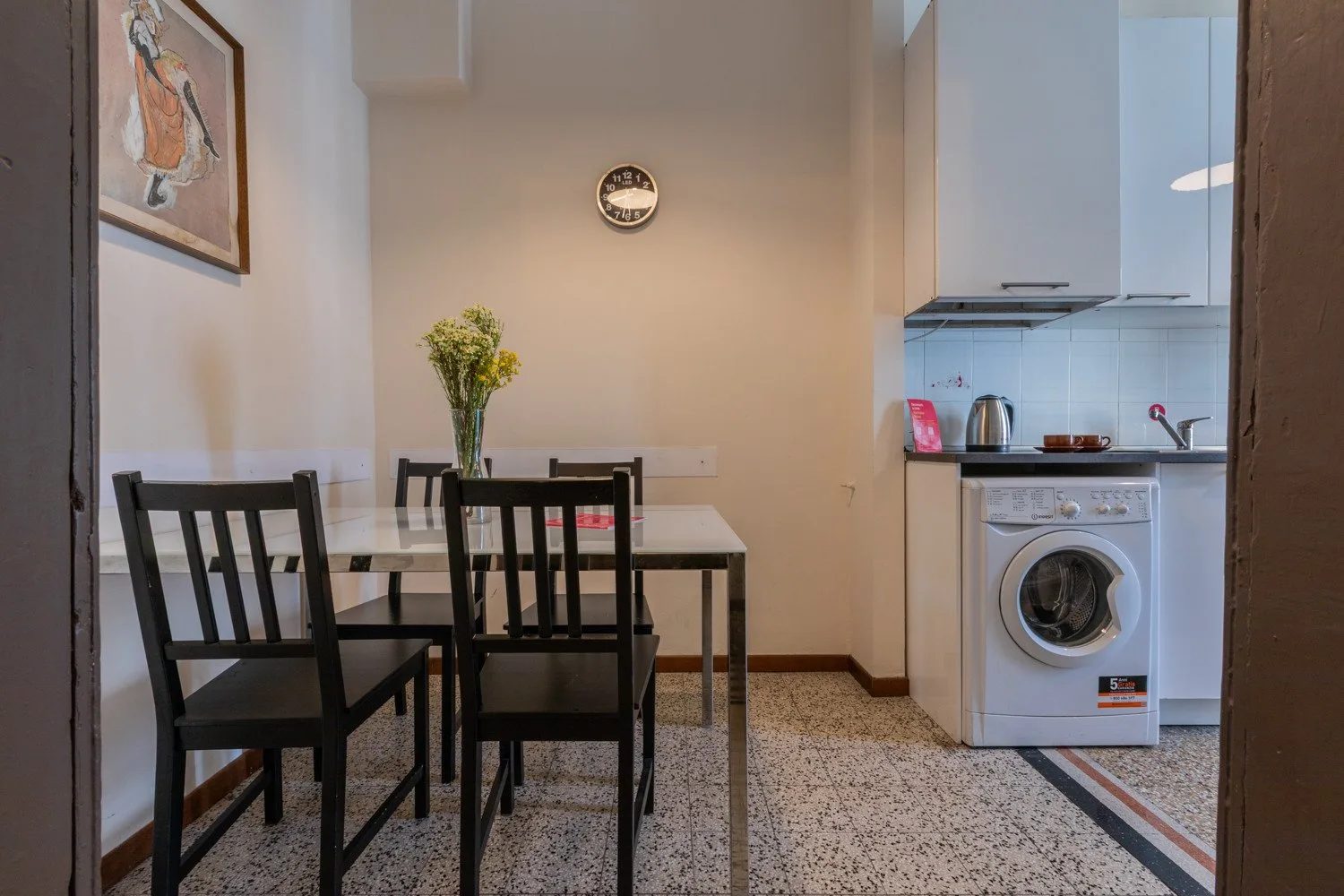 Un comedor con una mesa y sillas está junto a una cocina compacta.