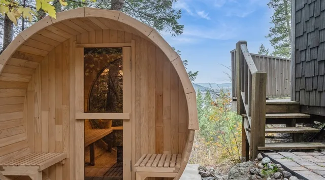 A small wooden cabin with a rounded roof and a window stands beside outdoor steps.