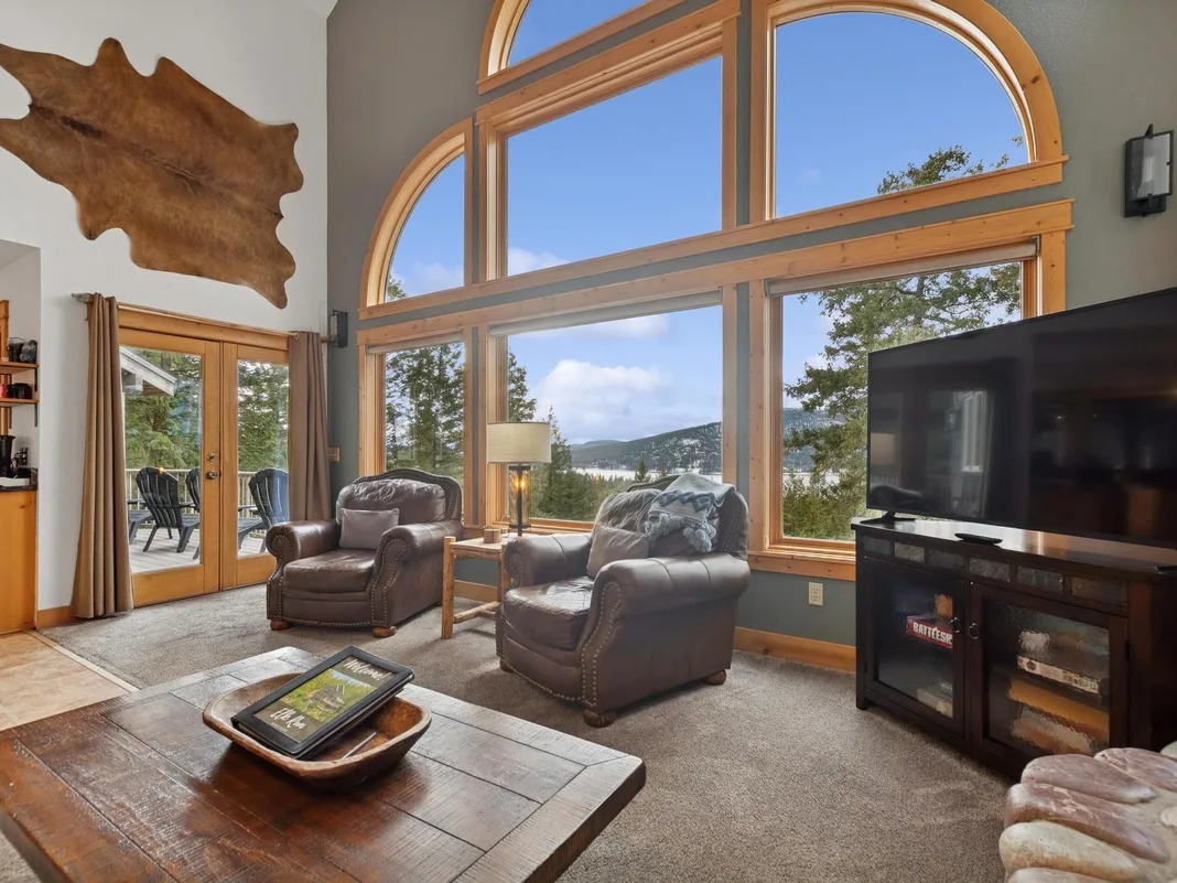 A living room with leather seating and a large television beside arched windows.