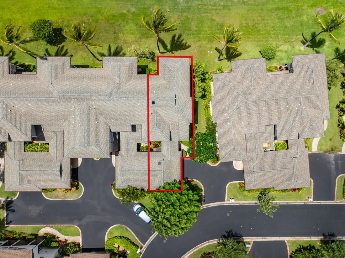 An aerial view shows several adjacent buildings beside a paved parking area and green lawn.