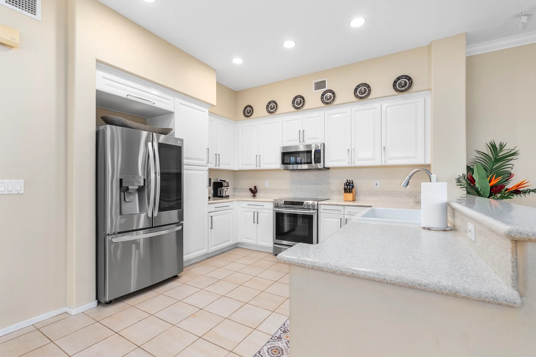 A bright kitchen with white cabinets and stainless-steel appliances.