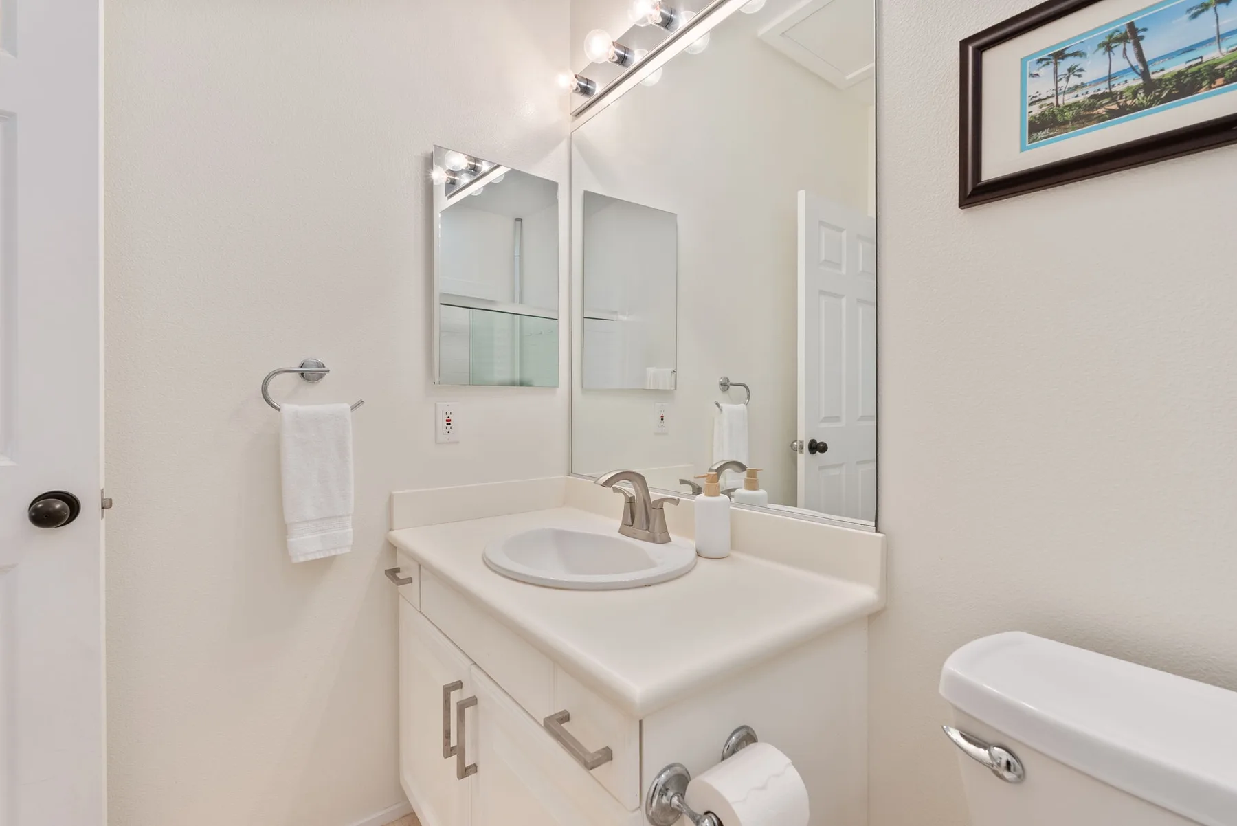 A bright bathroom with a sink vanity and wall mirror.