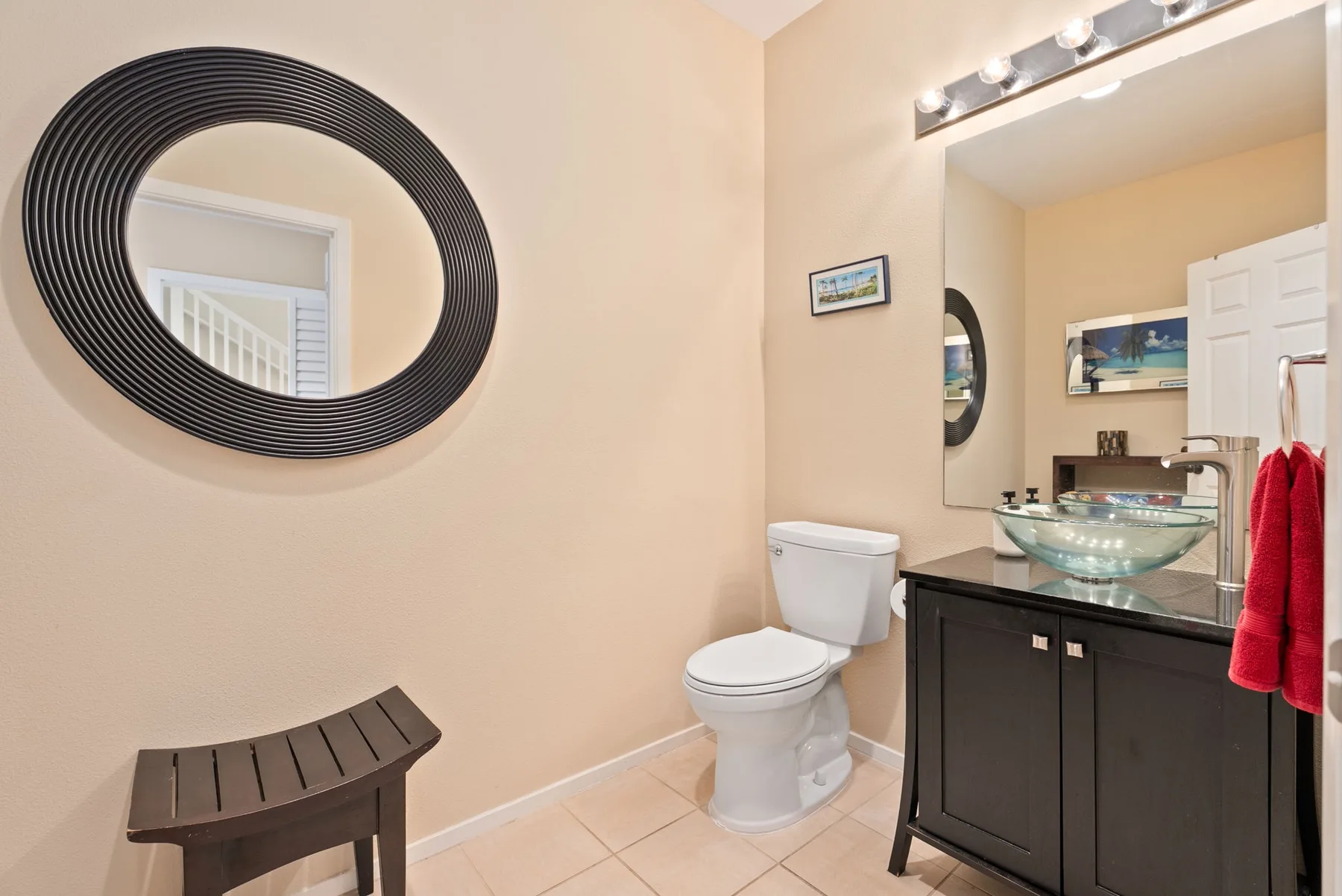 A bathroom with a toilet and a sink beneath a large mirror.