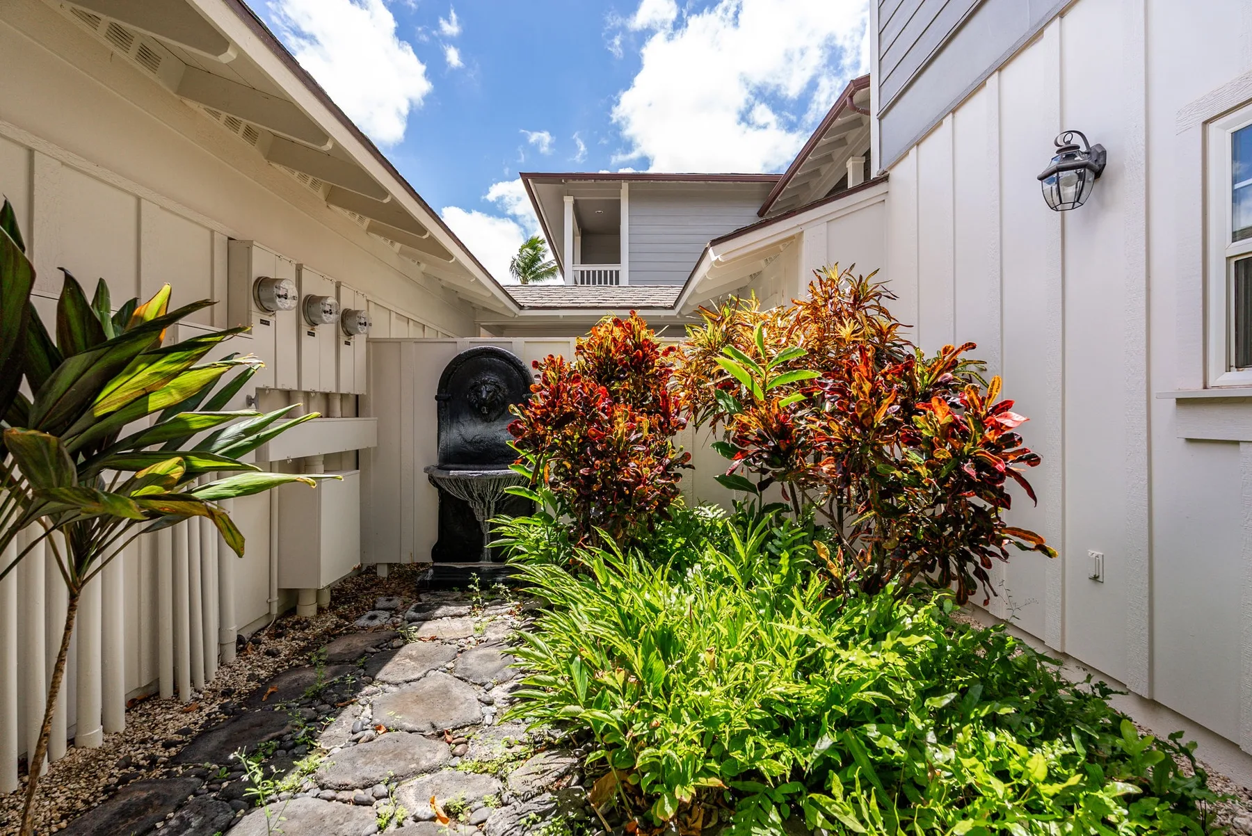 A stone path runs through a leafy outdoor courtyard between light-colored walls.