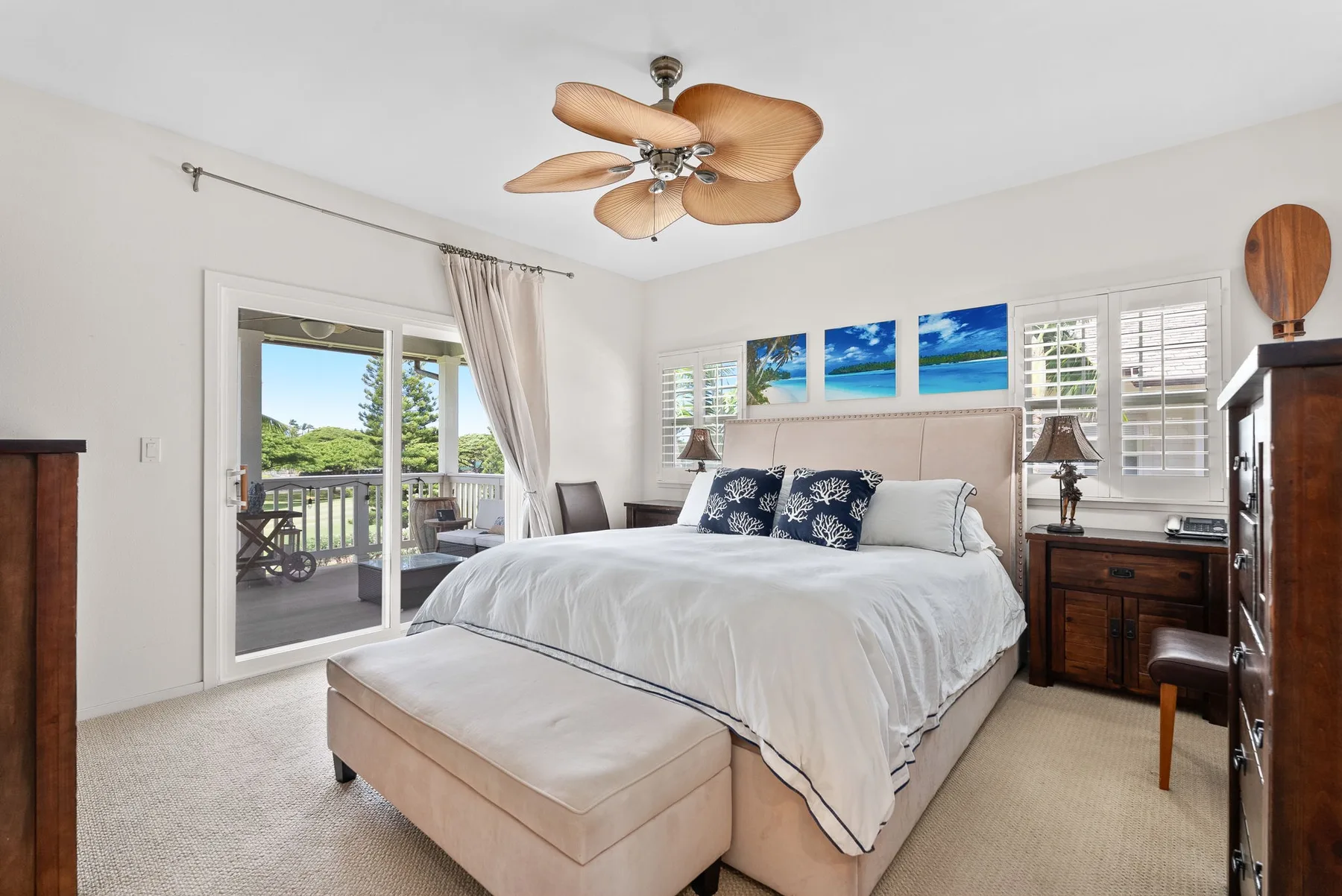 A bright bedroom with a large bed, bench, and balcony doors.