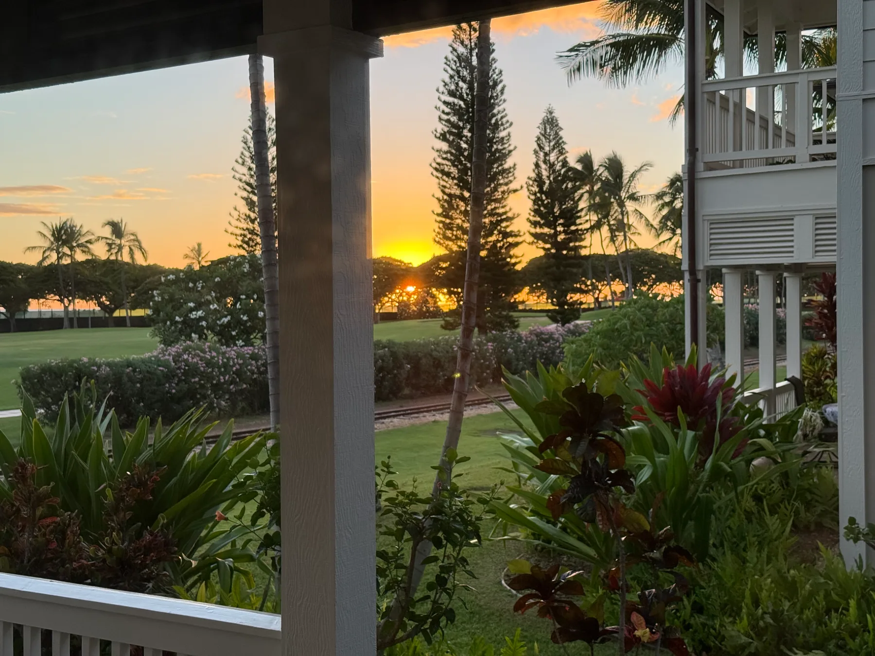 A covered outdoor patio overlooks a landscaped garden at sunset.