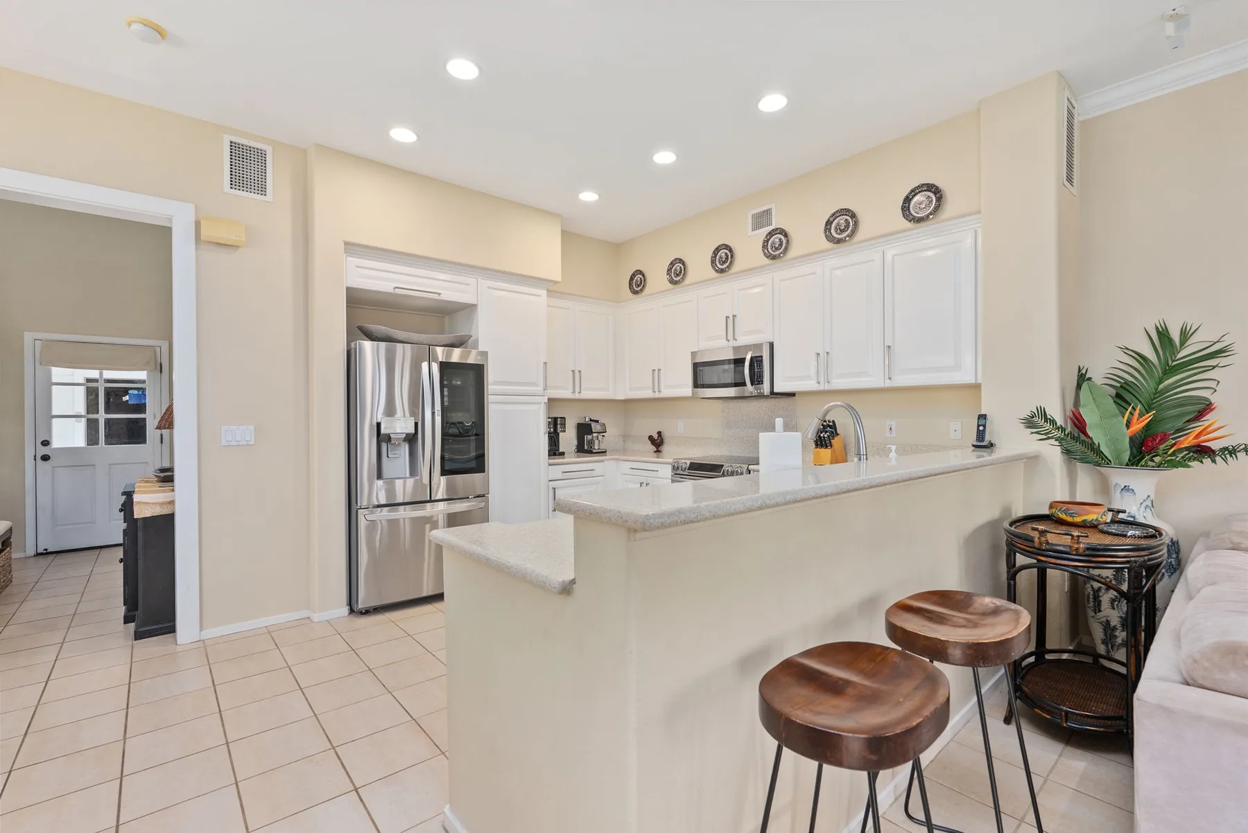 A bright kitchen with white cabinets, stainless steel appliances, and a breakfast counter.