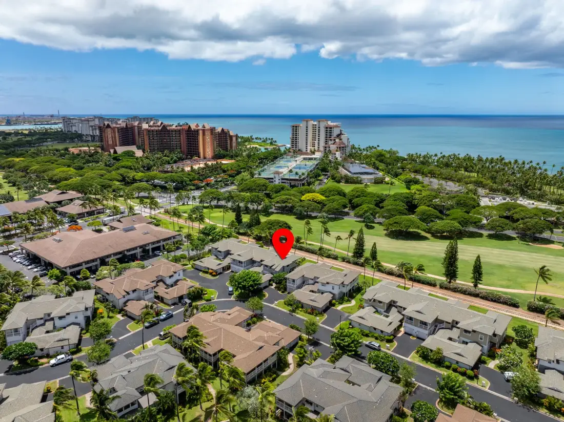 Aerial view of residential buildings, green grounds, and the ocean beyond.