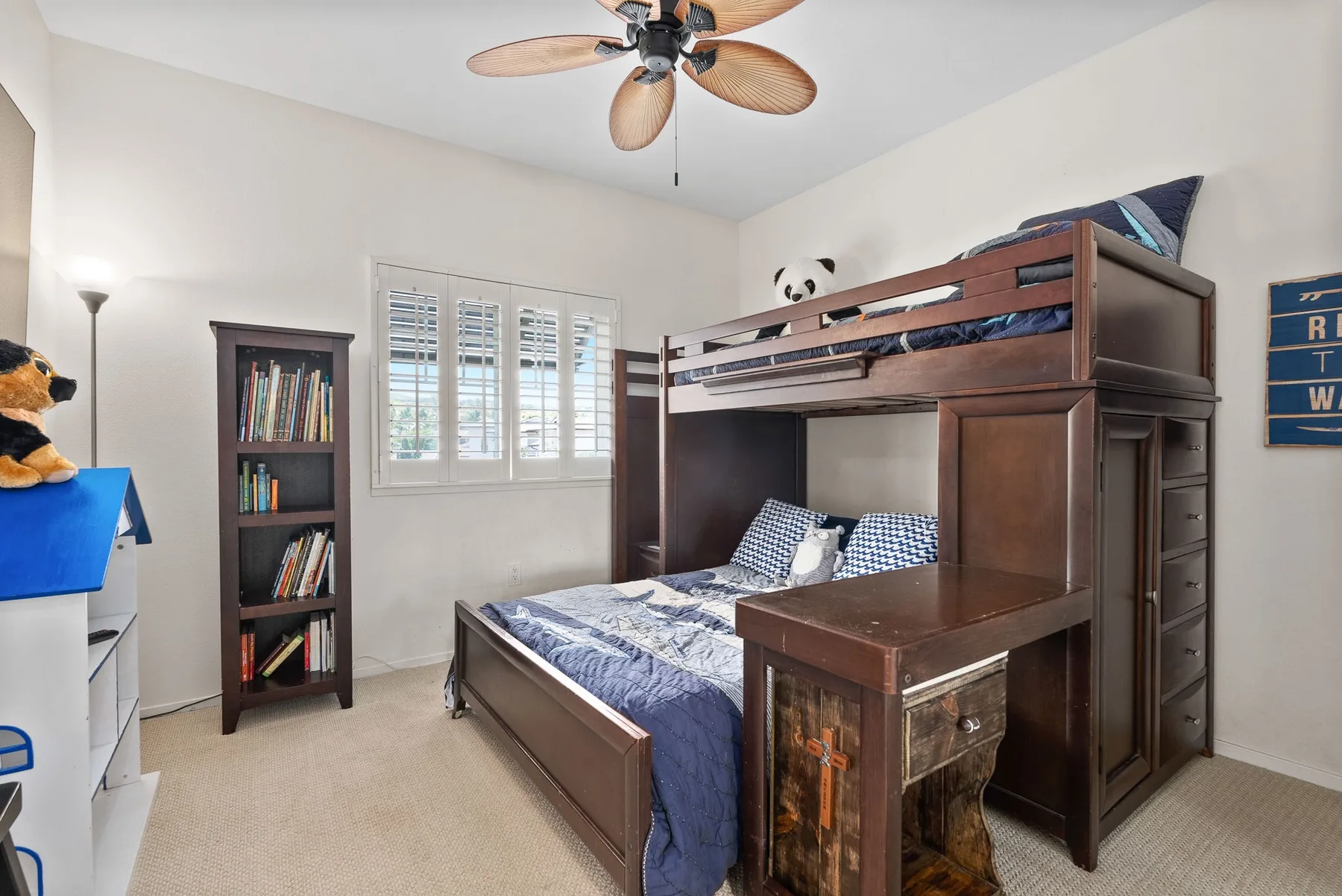 A bedroom with a wooden bunk bed, a window, and a bookshelf.