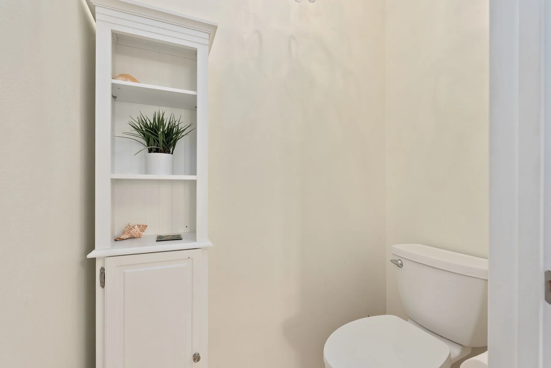 A bathroom with a built-in shelving unit beside the toilet.