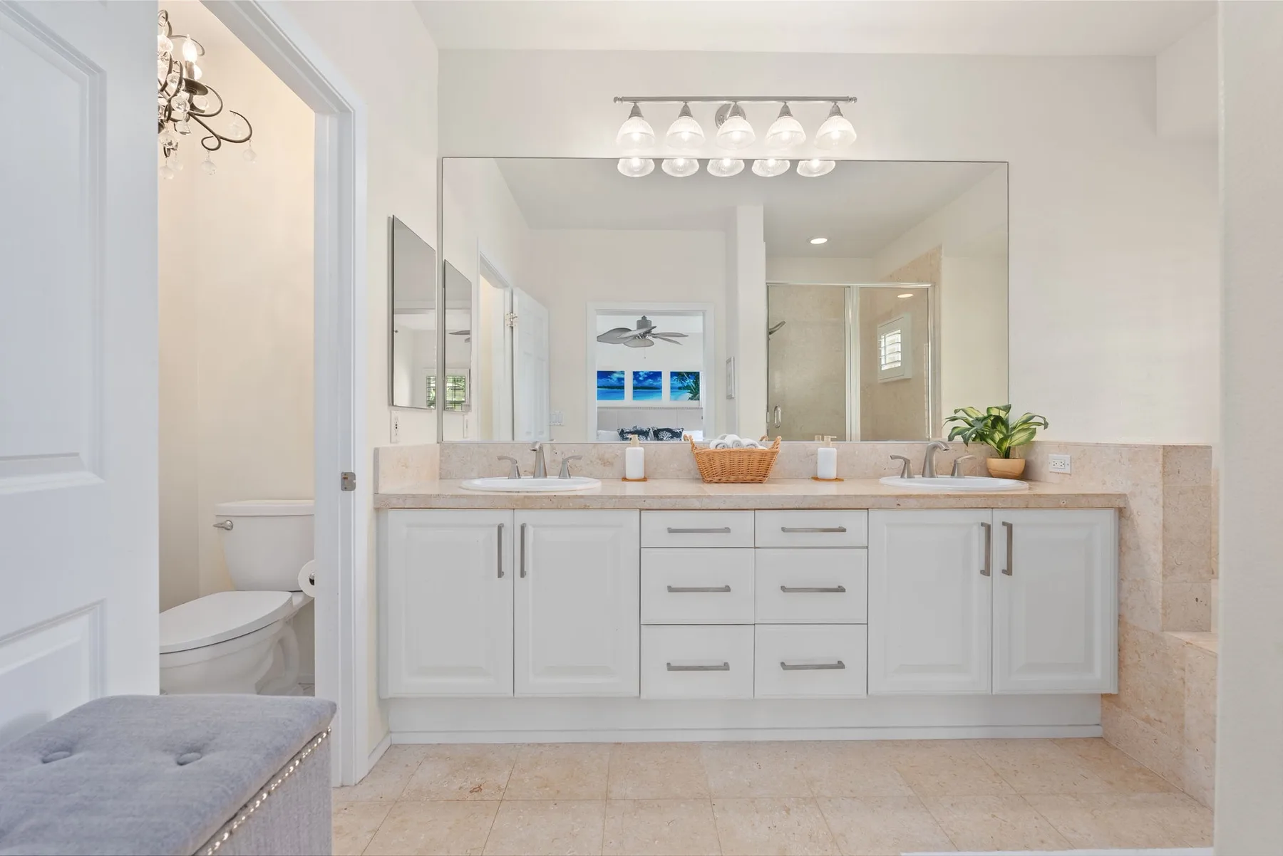 A bright bathroom with a long vanity, wide mirror, and bathtub visible in the reflection.