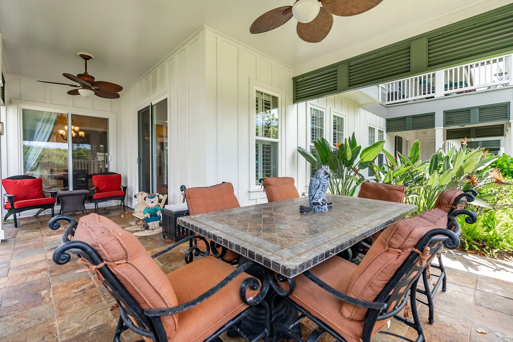 A covered patio dining area with a large table and cushioned seating.