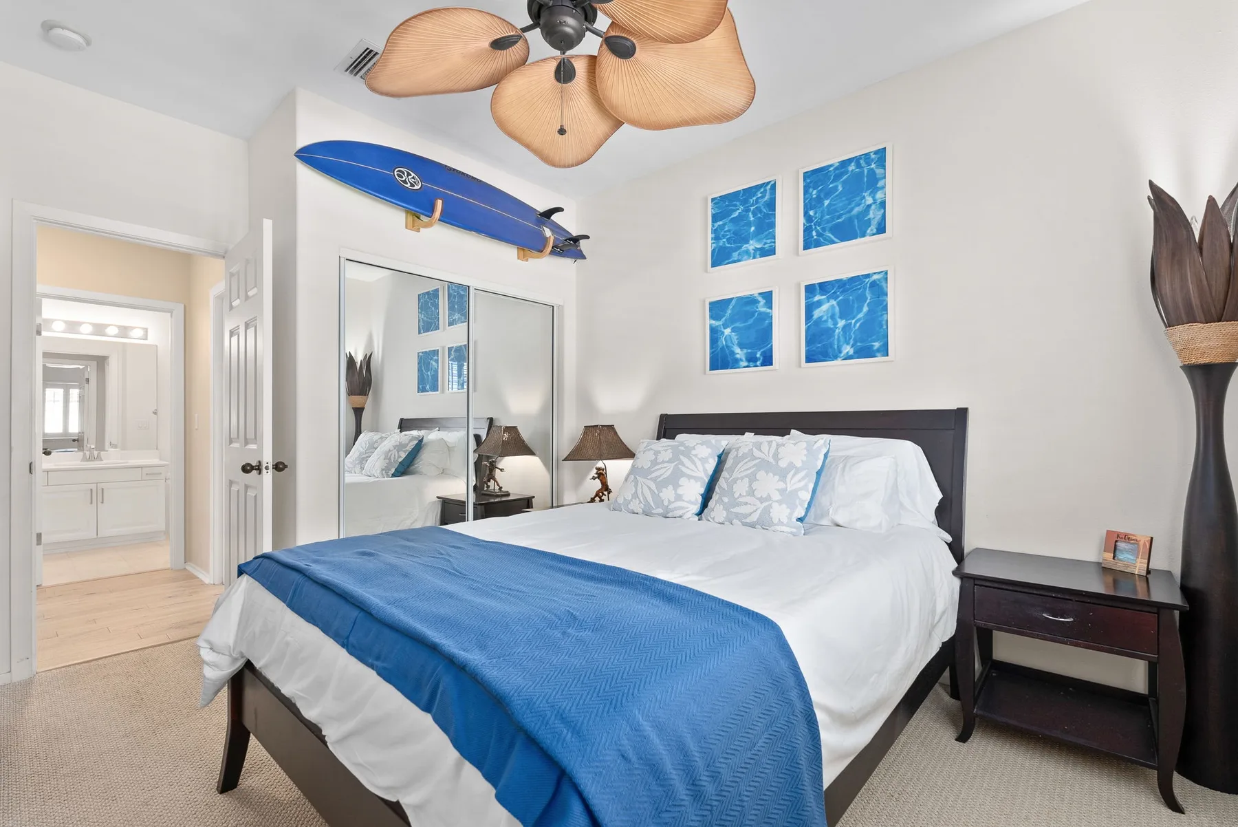 A bedroom with a bed covered in blue bedding and mirrored closet doors.