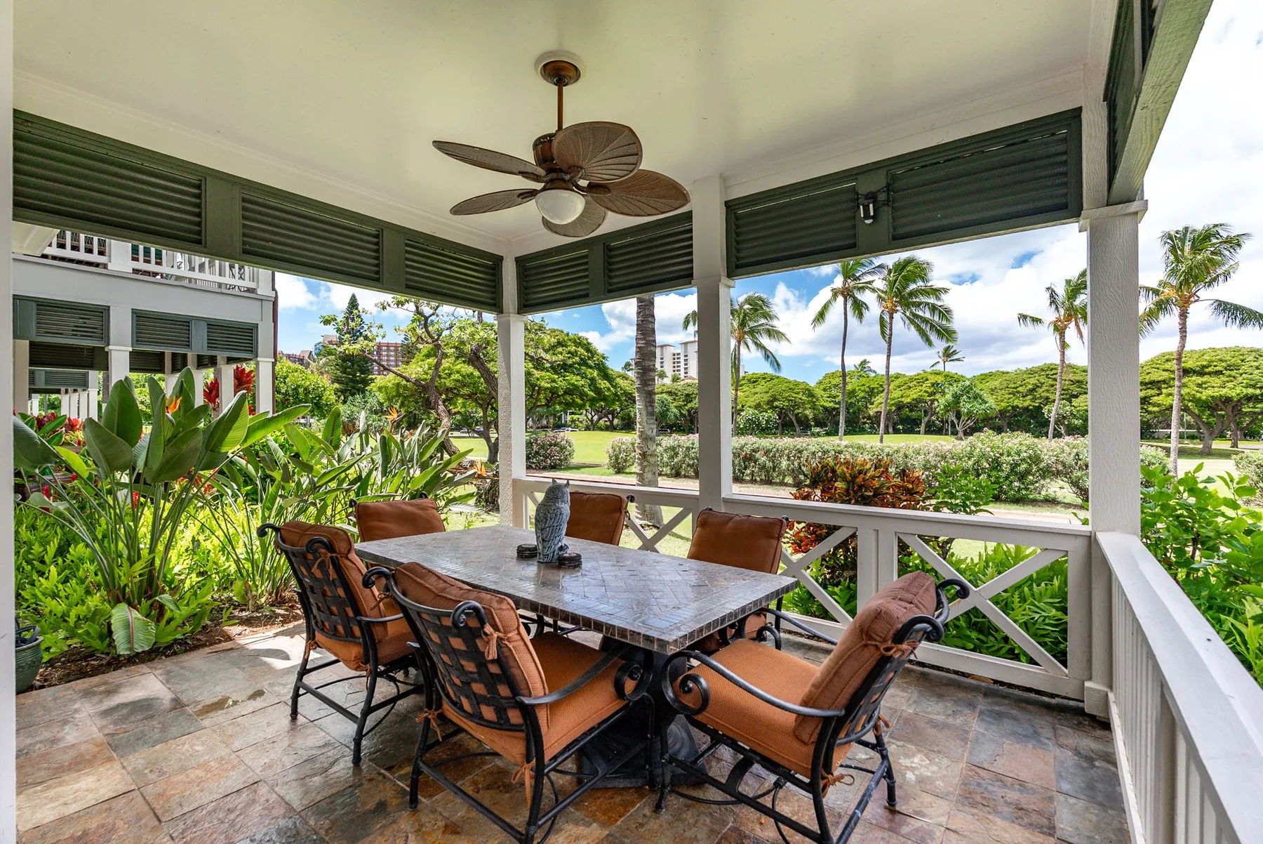 A covered outdoor dining area opens onto lush gardens and palm trees.
