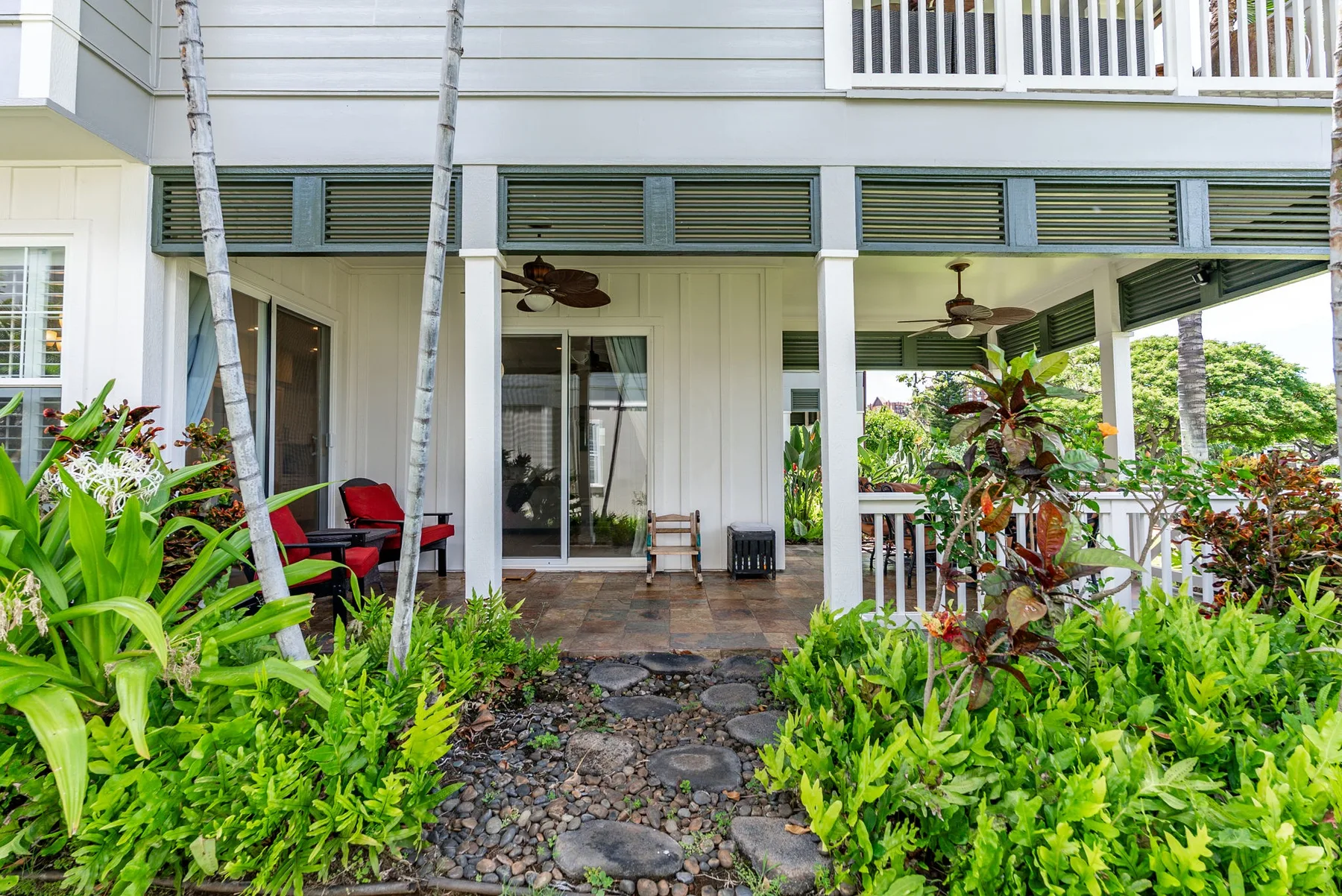 A covered patio with seating opens onto a garden path.