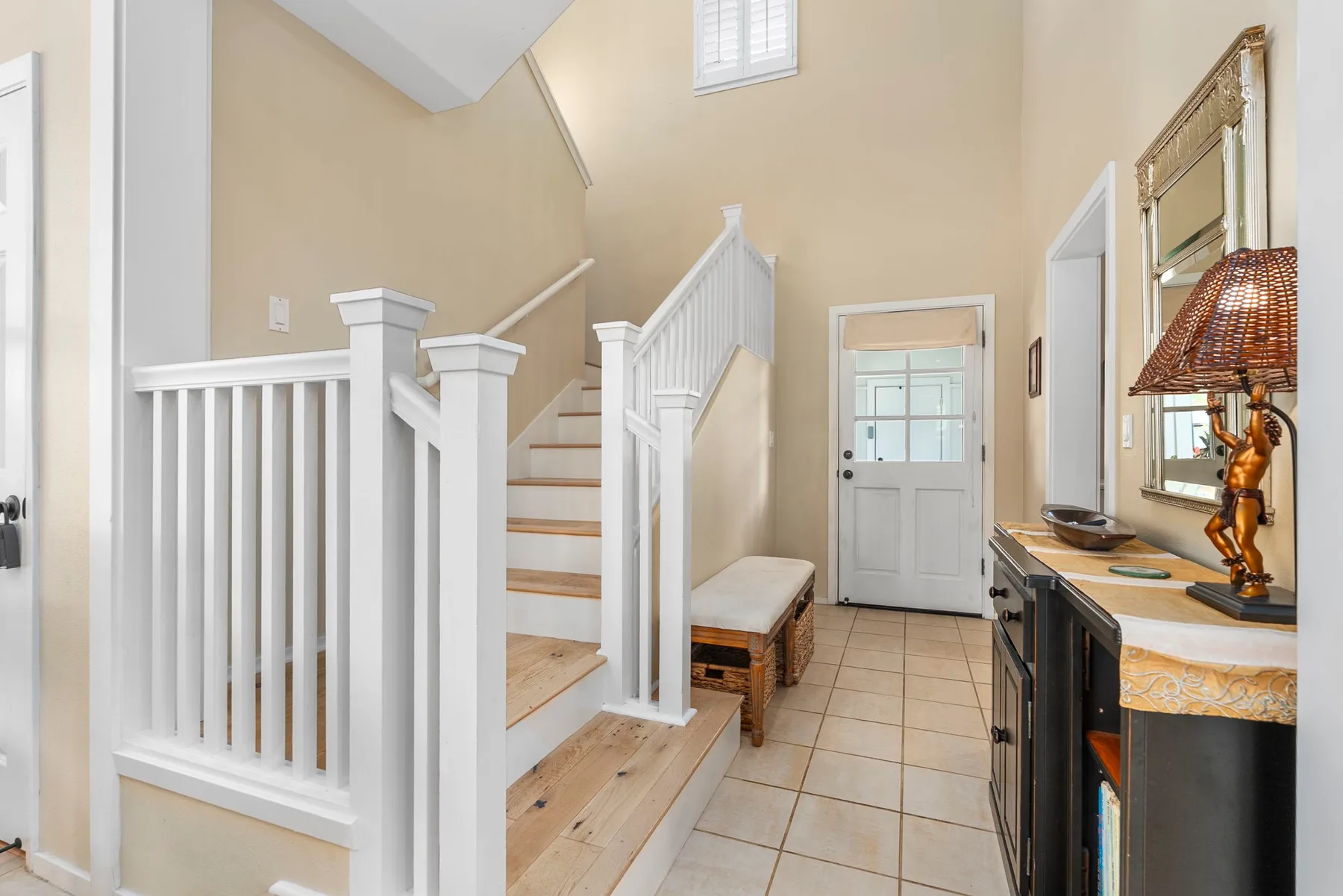 An interior entryway with a staircase, tiled floor, and a white door.