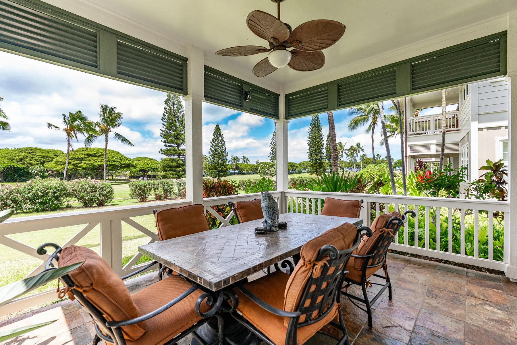A covered outdoor dining area with a table and seating overlooking greenery.