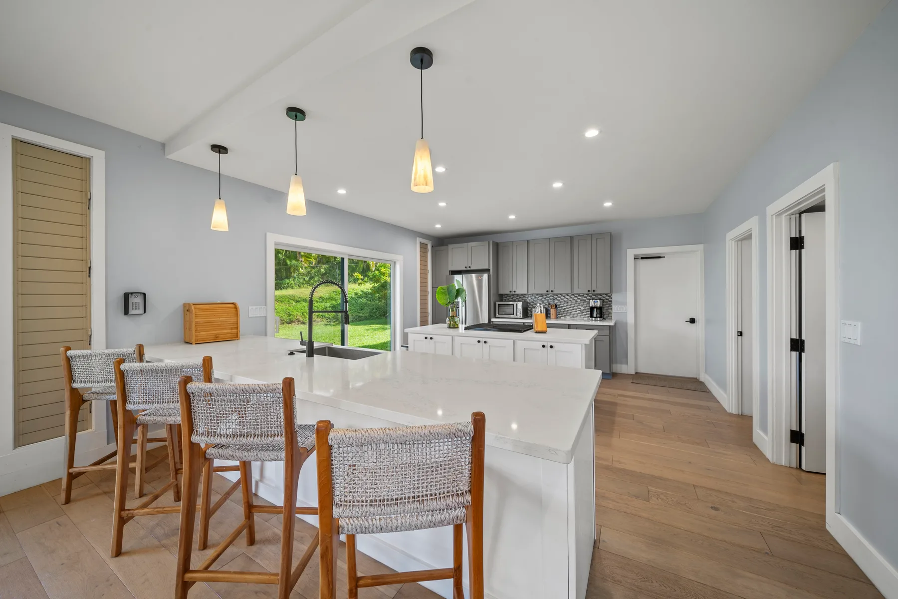 Una cocina y comedor luminosos con una isla grande y lámparas colgantes.