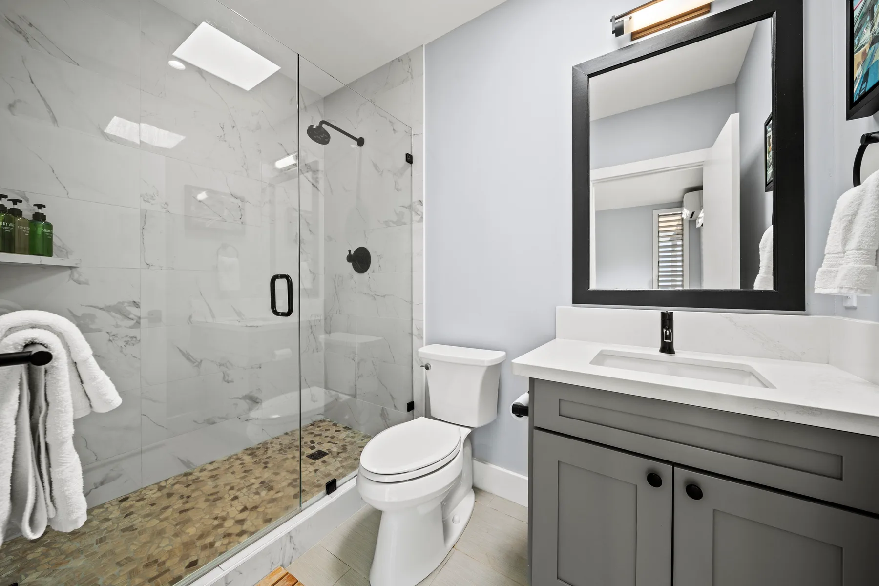 Un baño con ducha de vidrio, inodoro y lavabo con mueble.