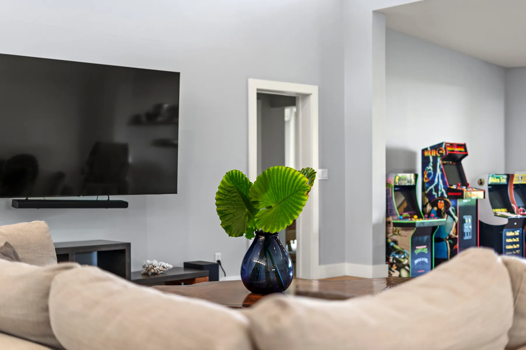 Una sala de estar con un televisor montado en la pared y máquinas recreativas a la vista.
