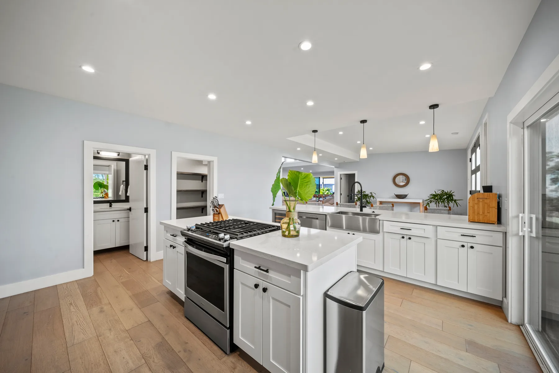 Una cocina luminosa con gabinetes blancos, una isla central y electrodomésticos de acero inoxidable.