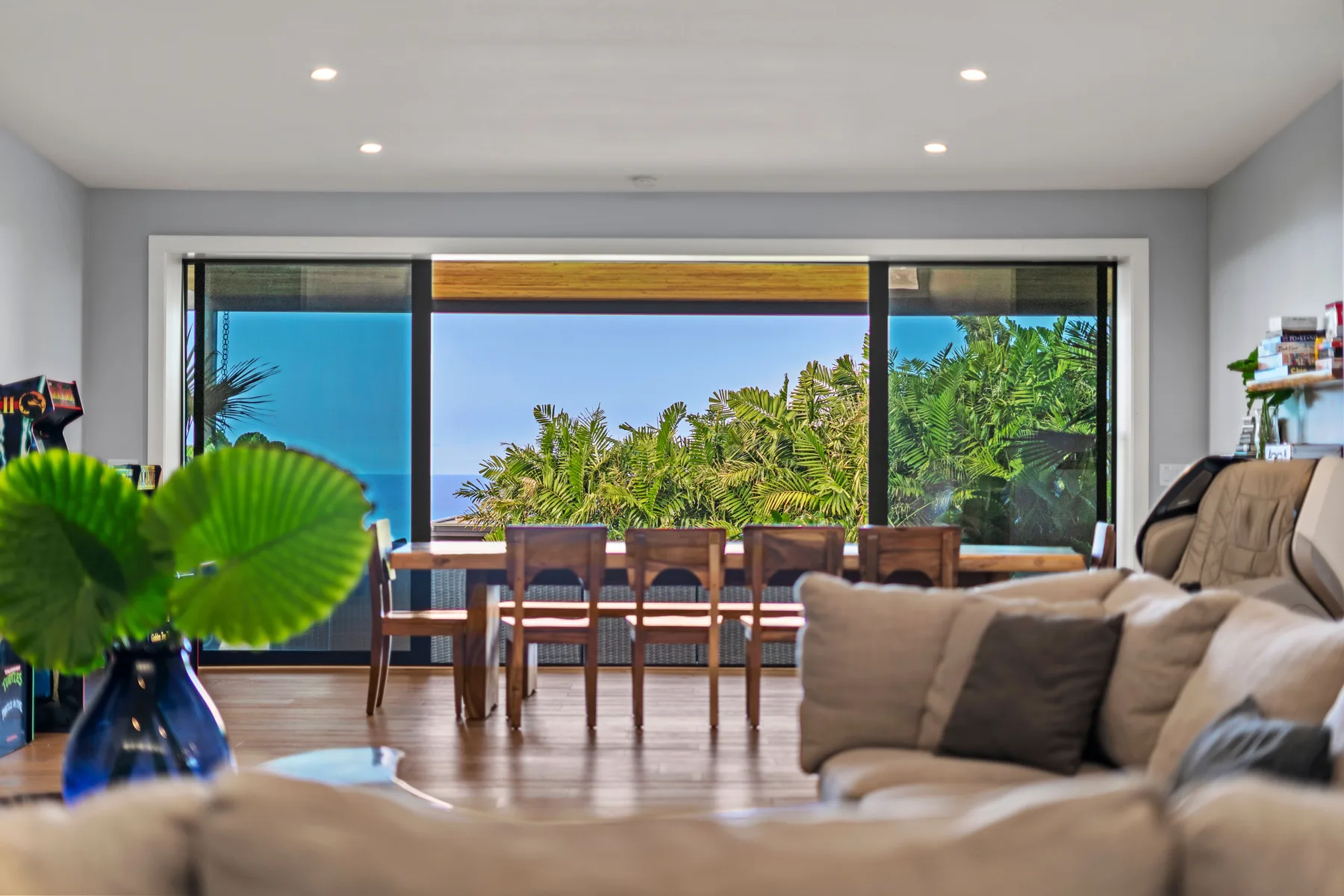 Una sala de estar y comedor se abre a grandes ventanales con vistas a la vegetación tropical.