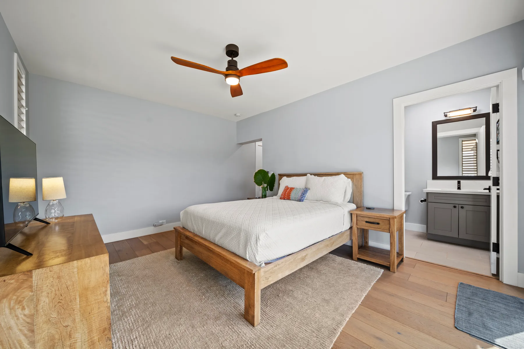 Un dormitorio con una cama de madera, mesitas de noche y un ventilador de techo.