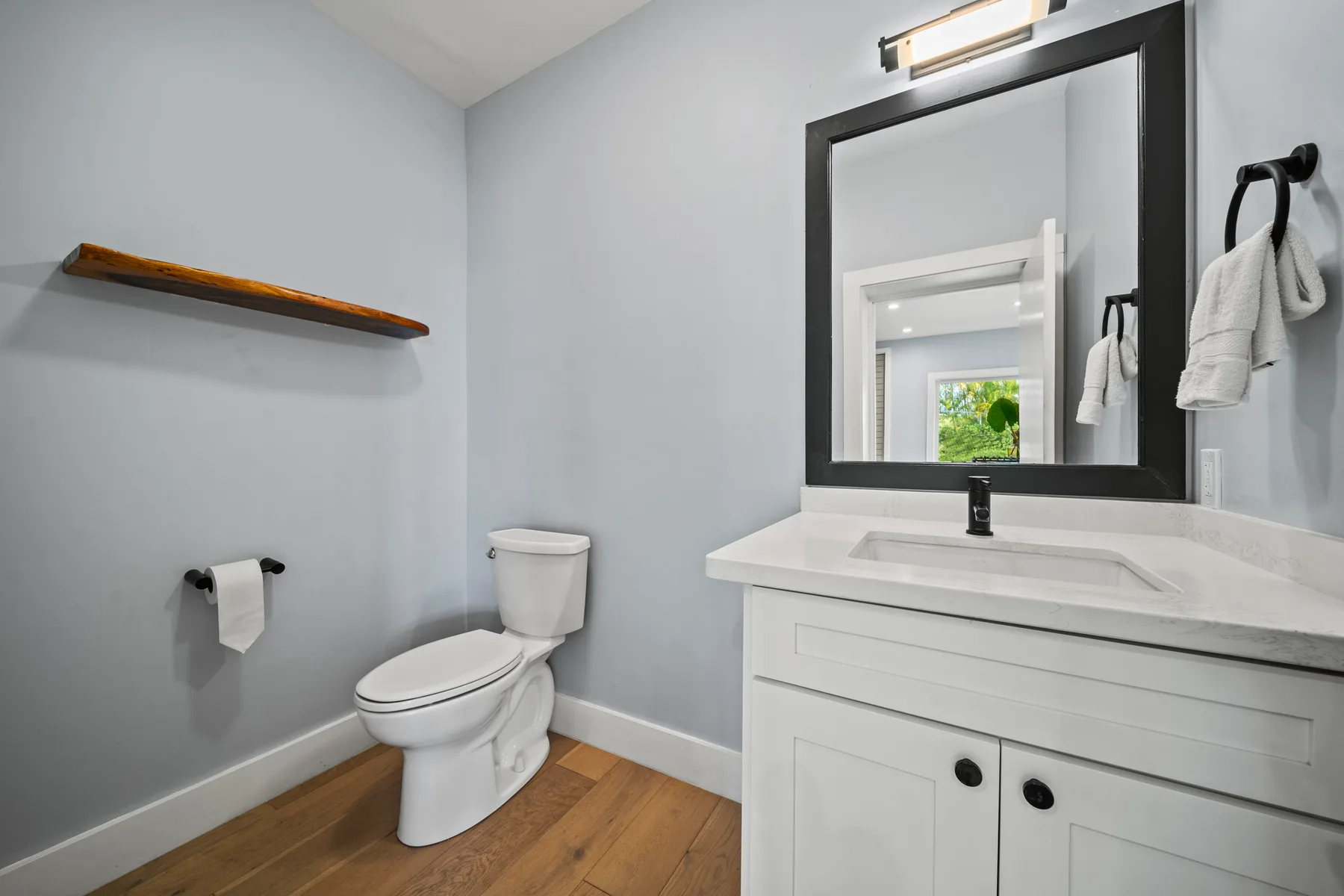Un baño con mueble de lavabo blanco, espejo e inodoro.