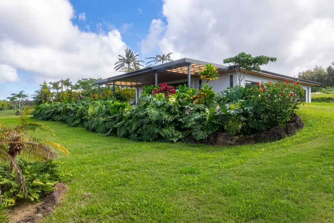 Una casa moderna se encuentra detrás de arbustos floridos en un amplio césped verde.