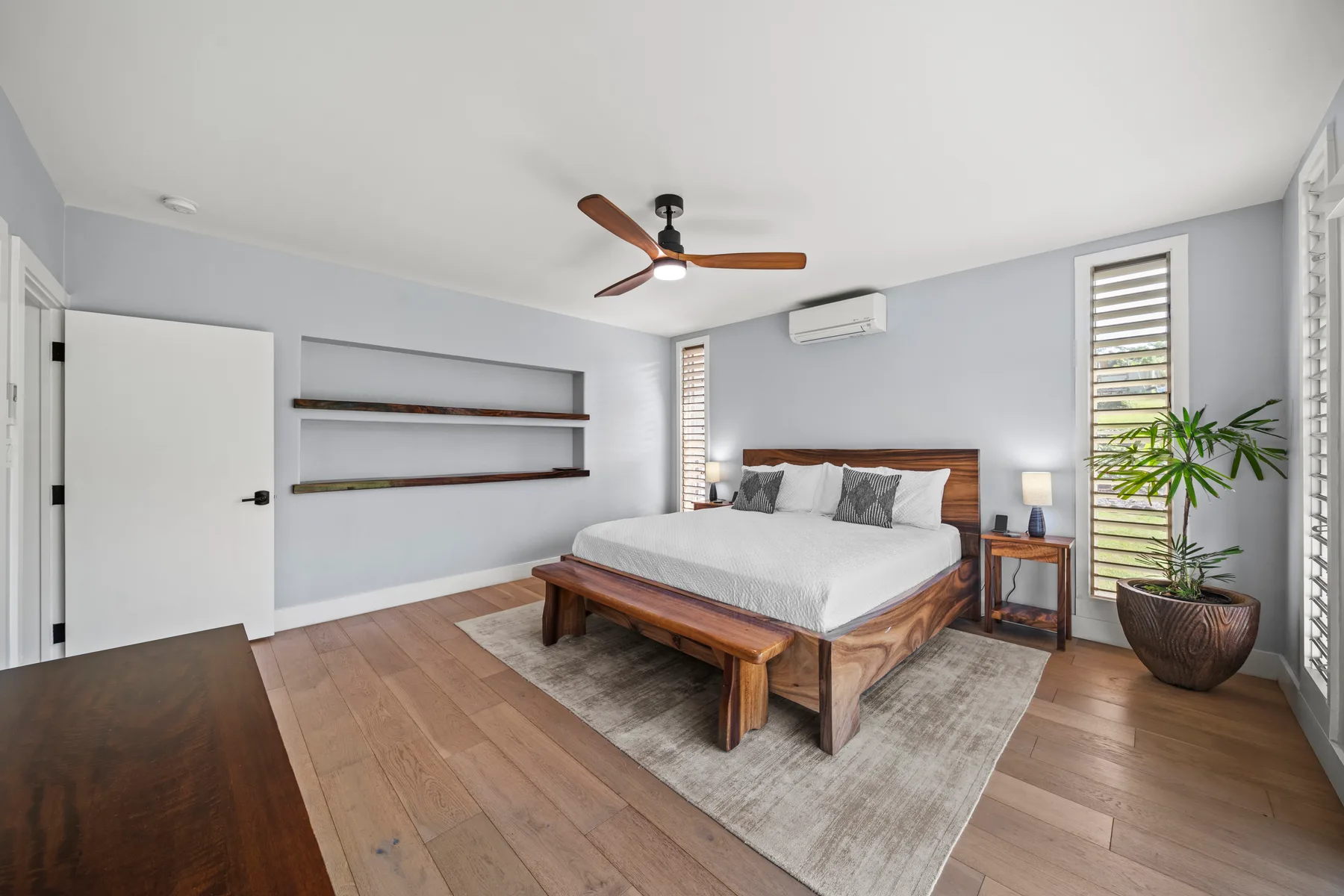 Un dormitorio con una cama de madera, mesitas de noche y una planta en maceta.