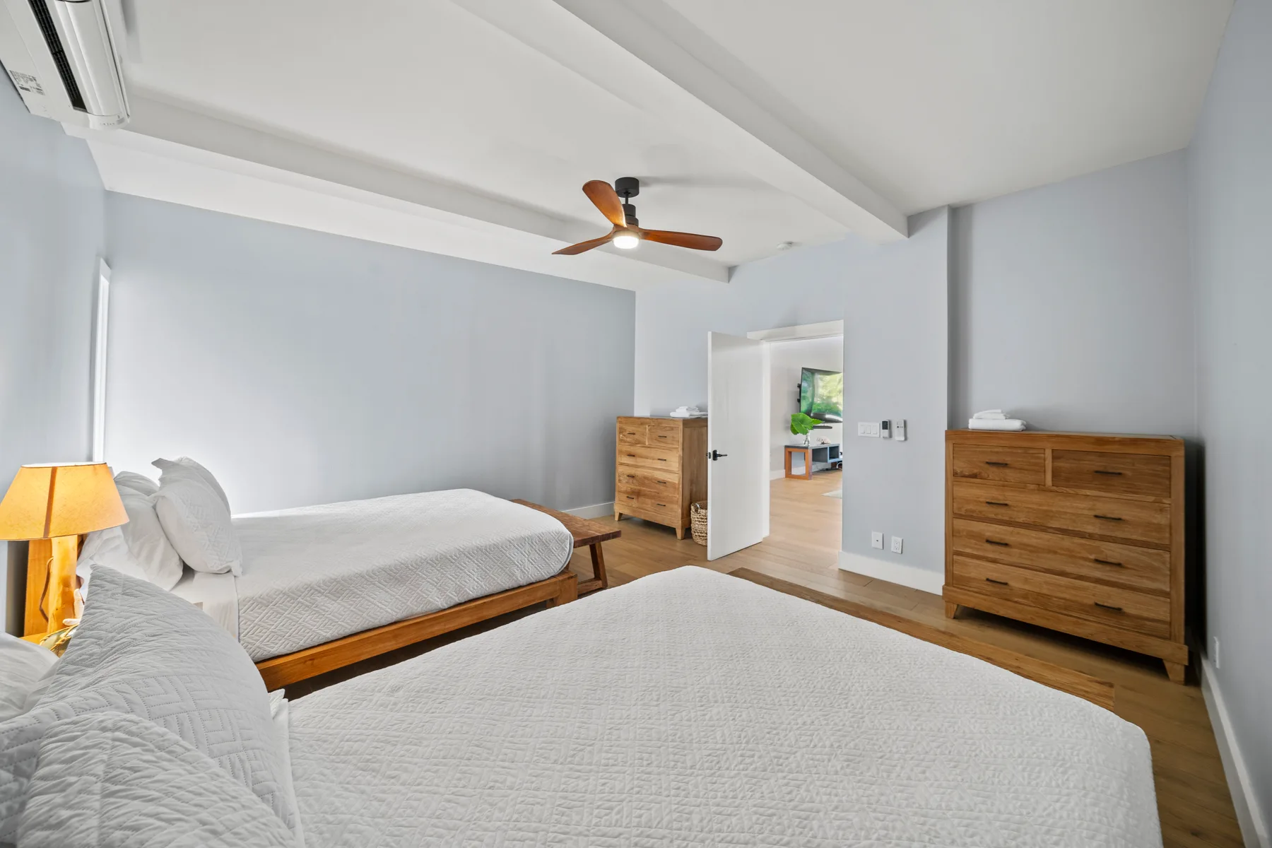 Un dormitorio con camas, cómodas de madera y un ventilador de techo.