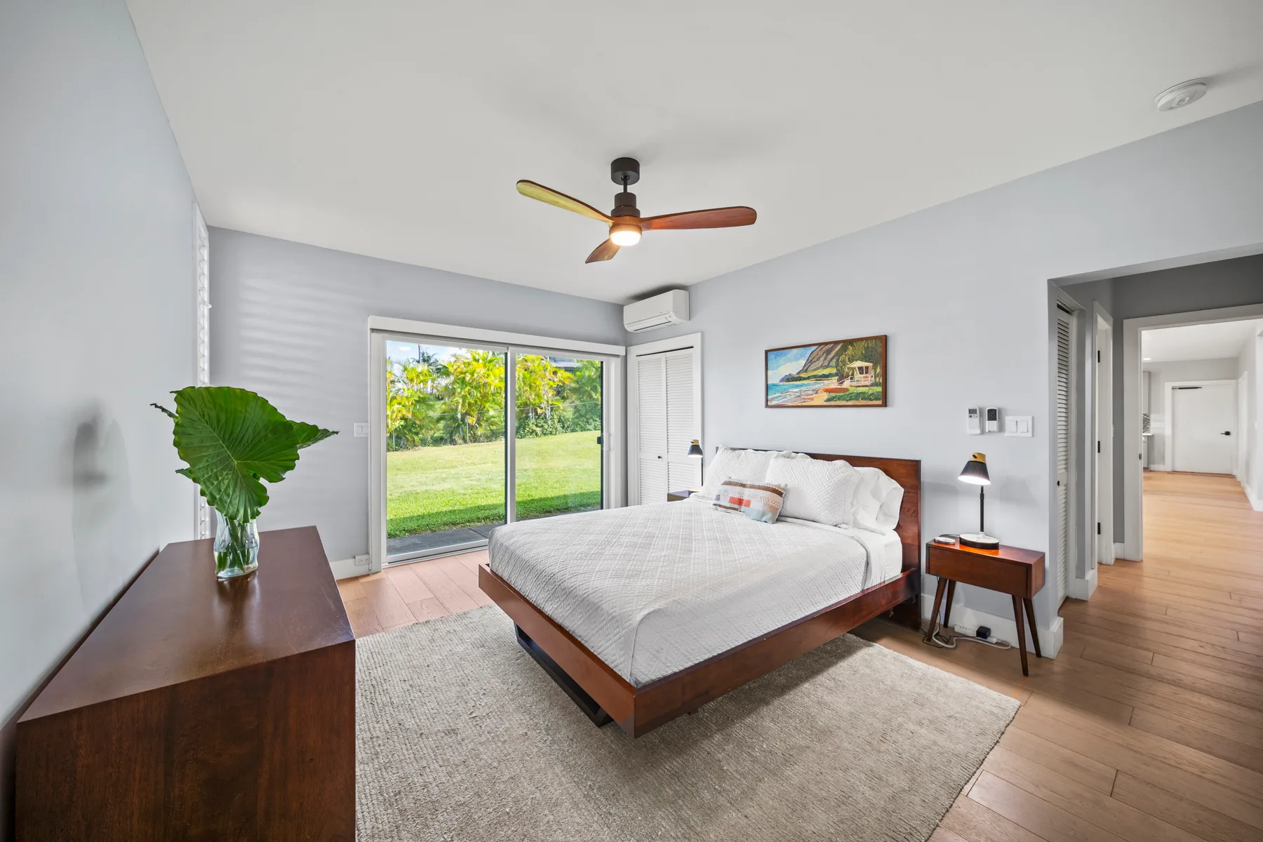 Un dormitorio luminoso con una cama junto a puertas corredizas de vidrio que dan a un jardín.